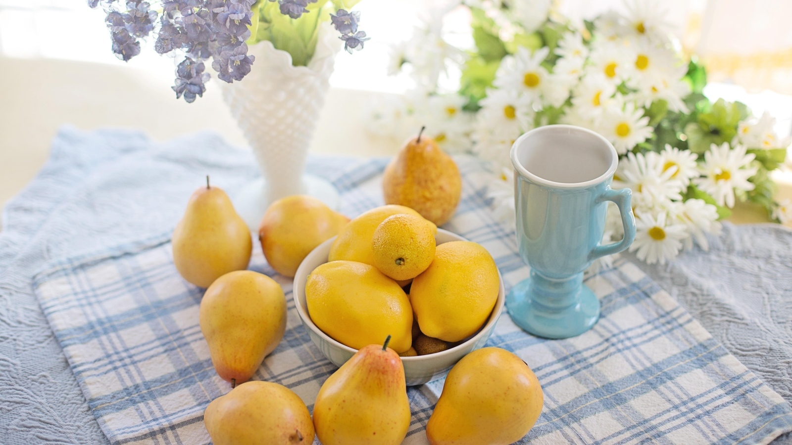 Лимоны и груши на столе с цветами