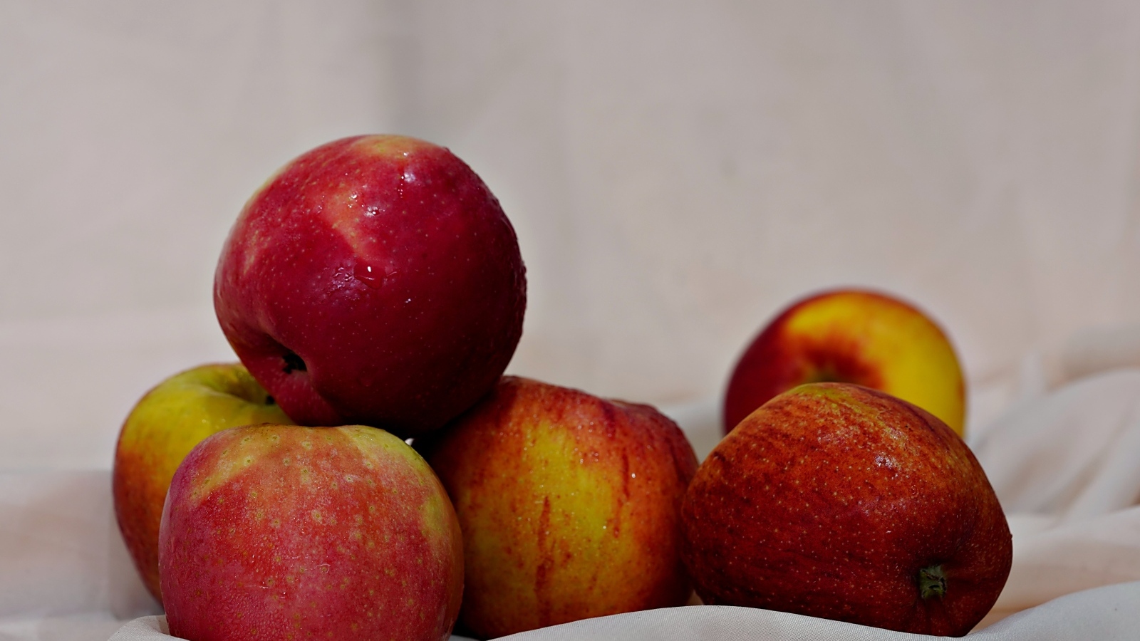 Много красных яблок с белой тканью 