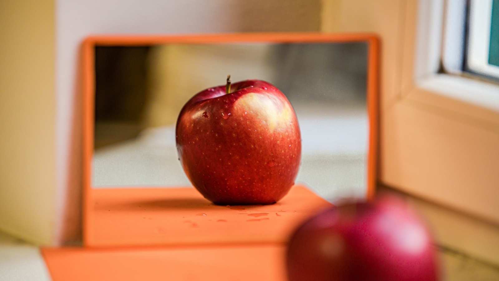 Больше красное яблоко отражается в зеркале 