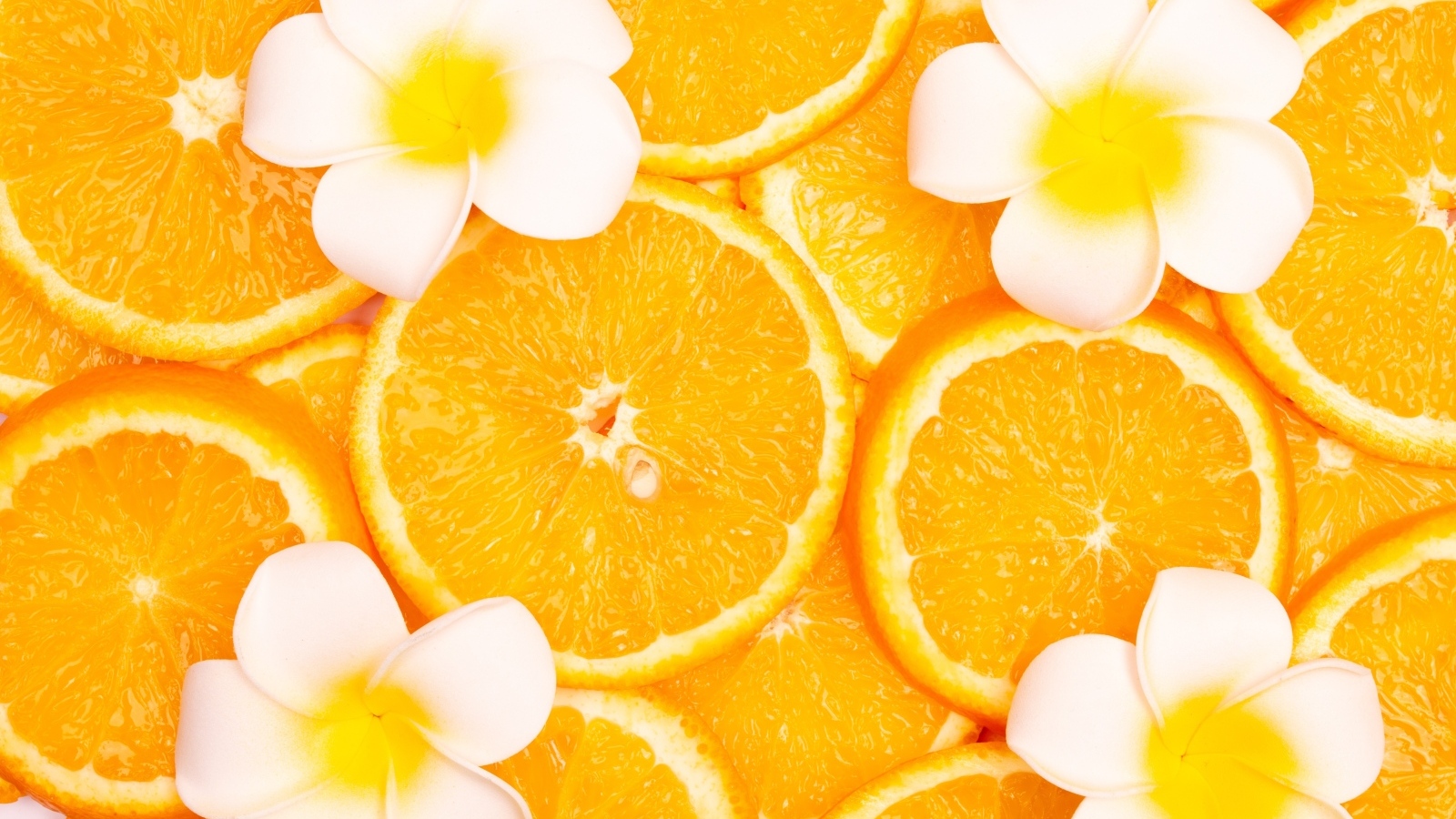 Кружочки апельсина с цветами плюмерии крупным планом