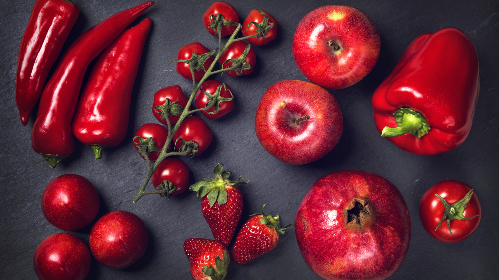Красные овощи и фрукты на сером столе