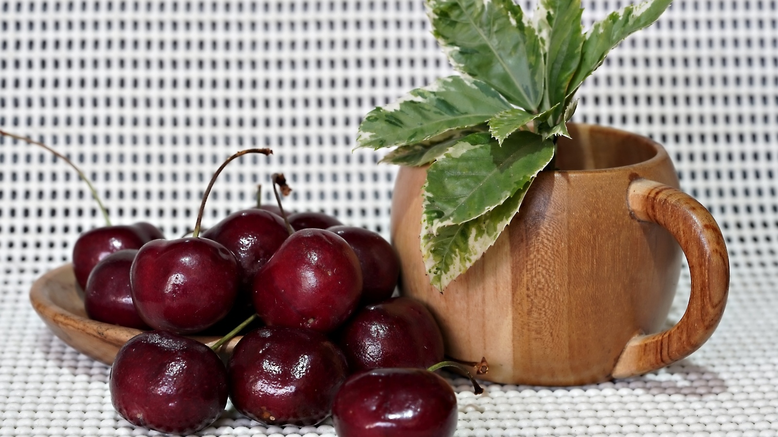 Спелые красные черешни на столе с цветком