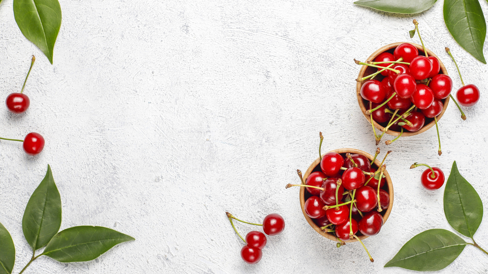 Спелая красная вишня с зелеными листьями на столе