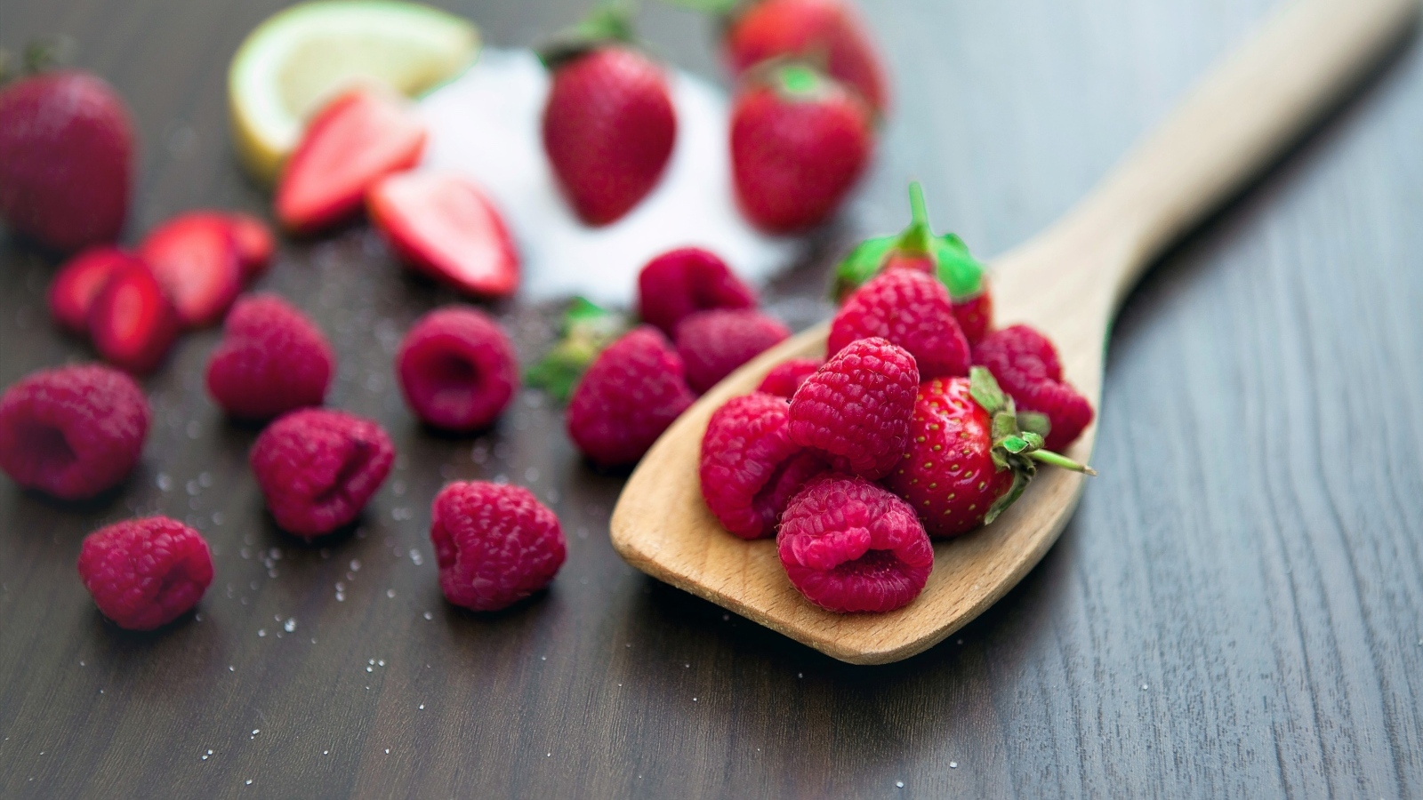 Спелая красная малина с деревянной ложкой на столе