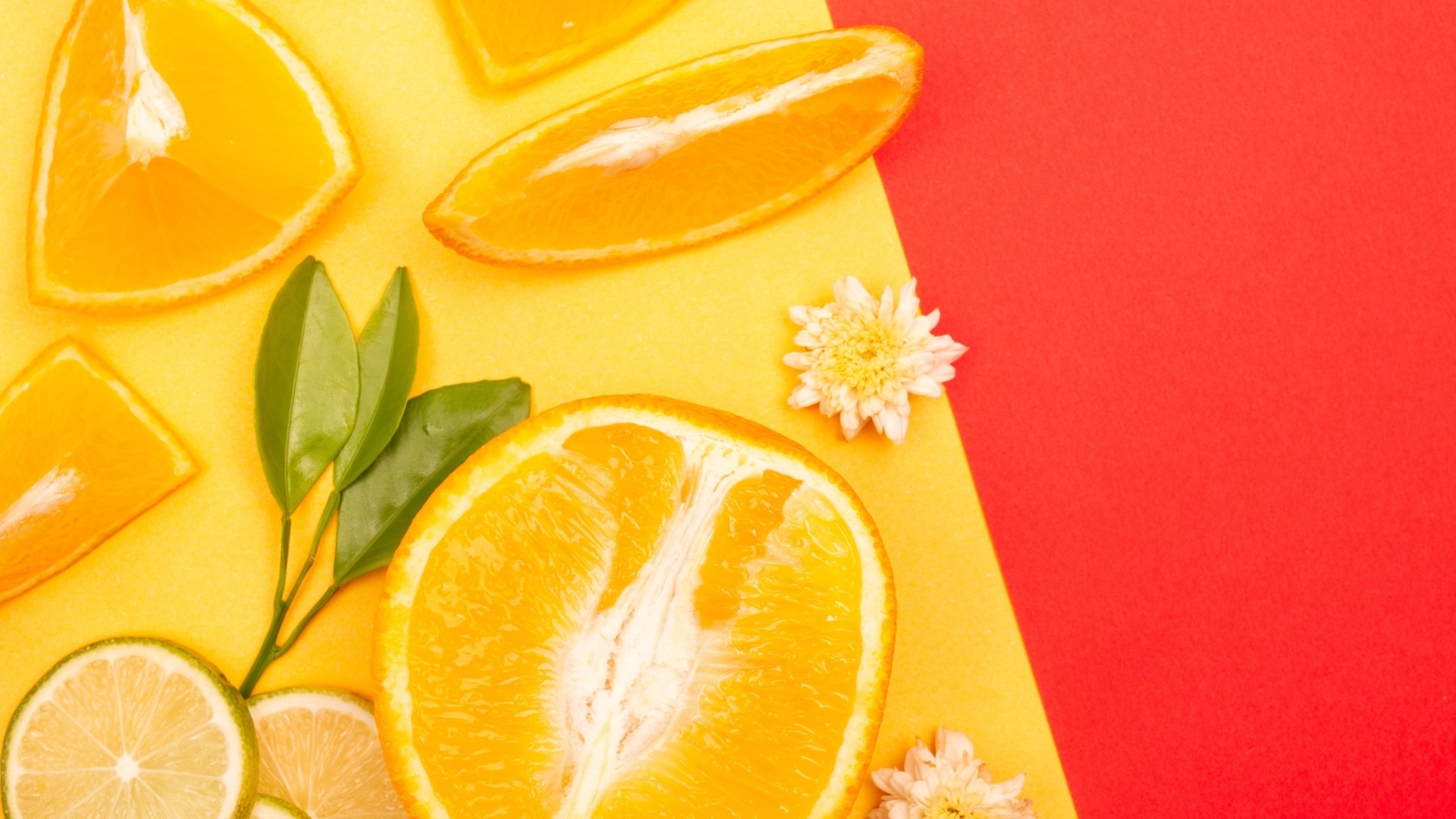 Кусочки апельсина и лайма на разноцветной поверхности 