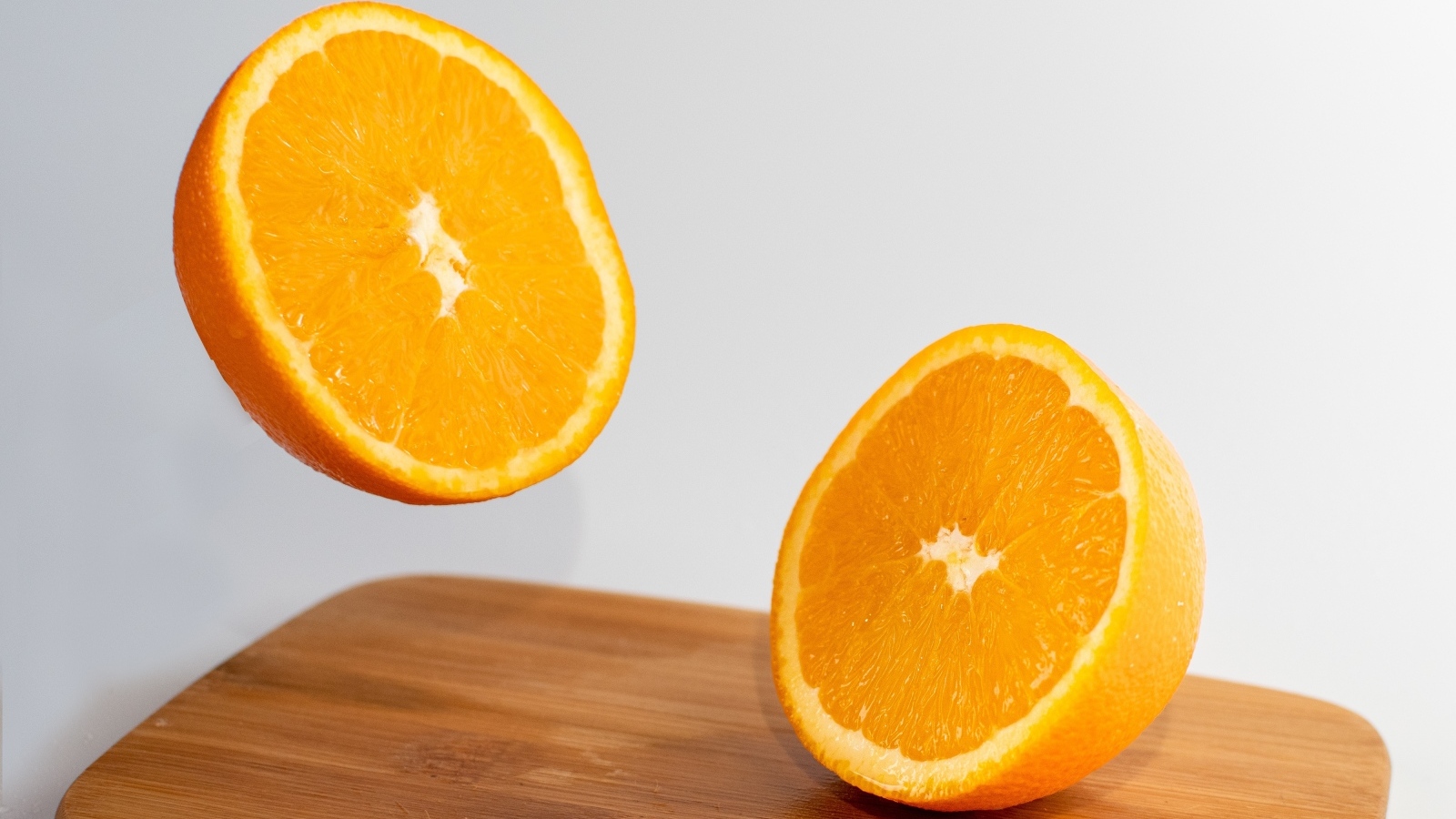 Две половинки апельсина на деревянной доске
