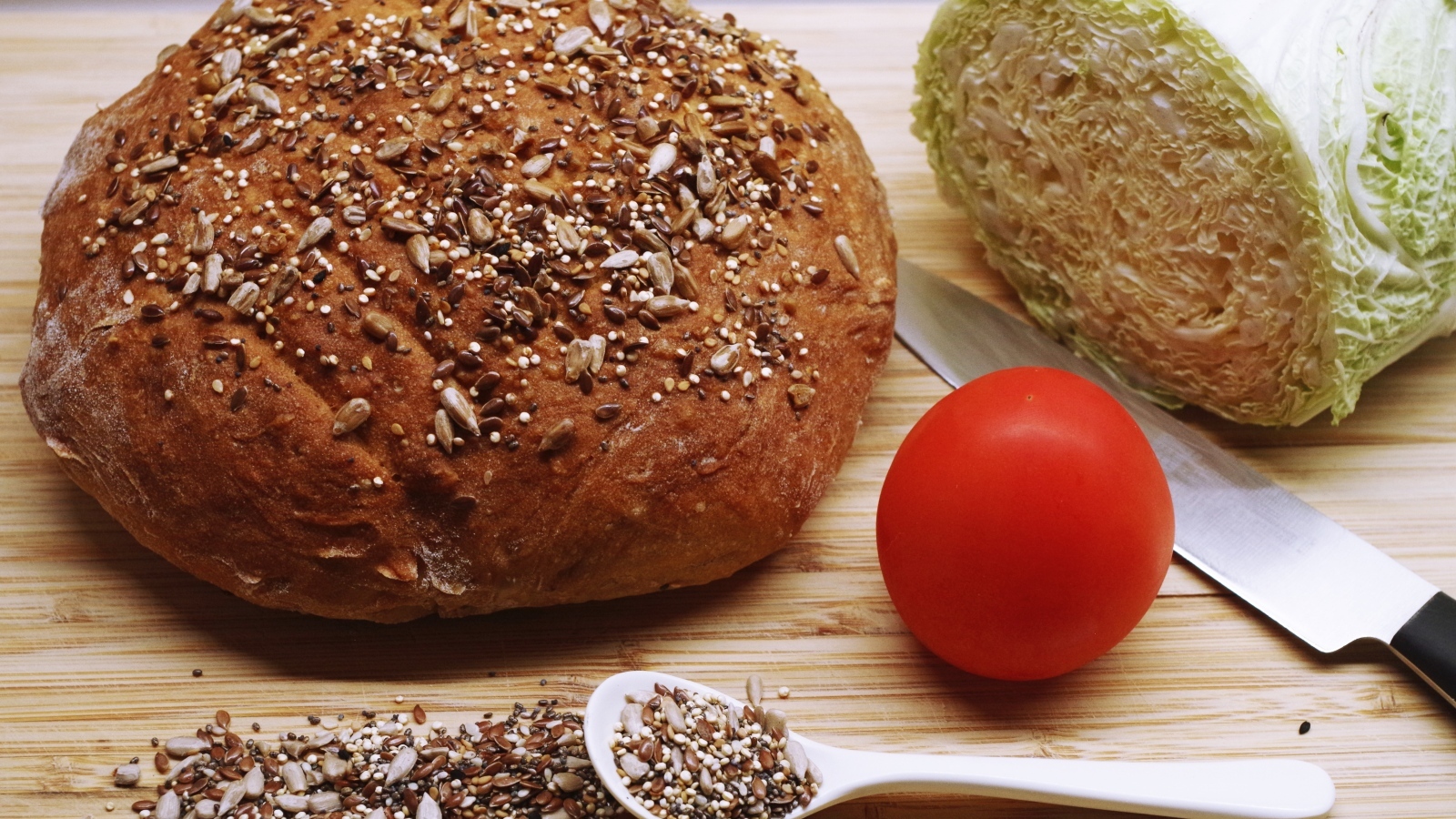 Буханка хлеба на столе с капустой и помидором