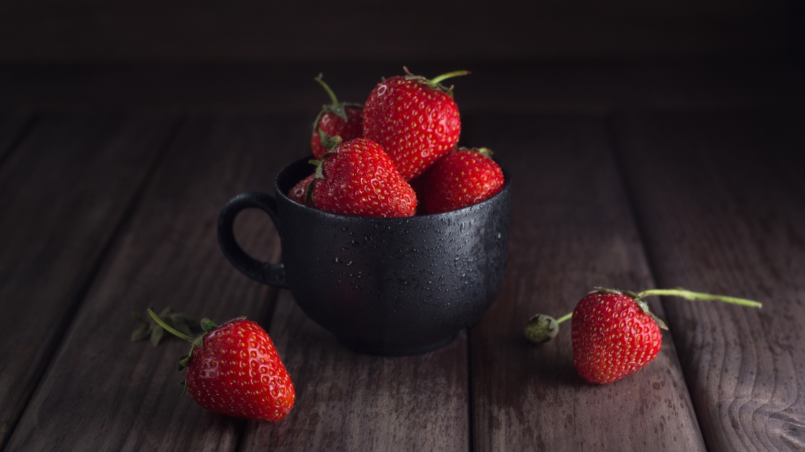 Черная чашка с красными ягодами клубники