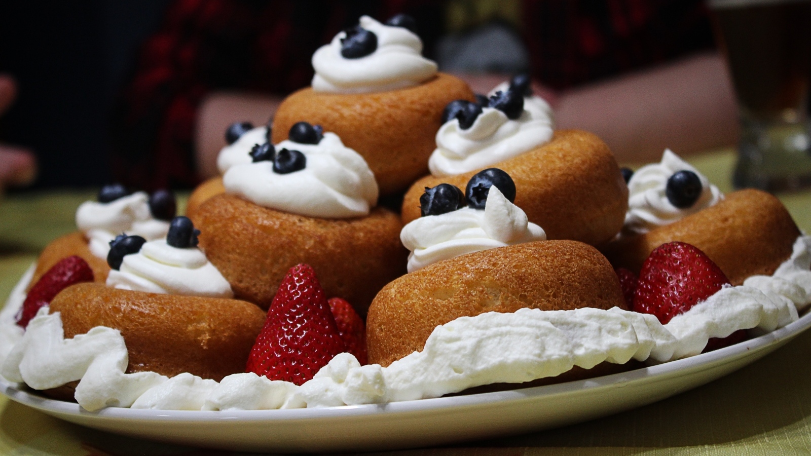 Пирожные на тарелке со взбитыми сливками и ягодами