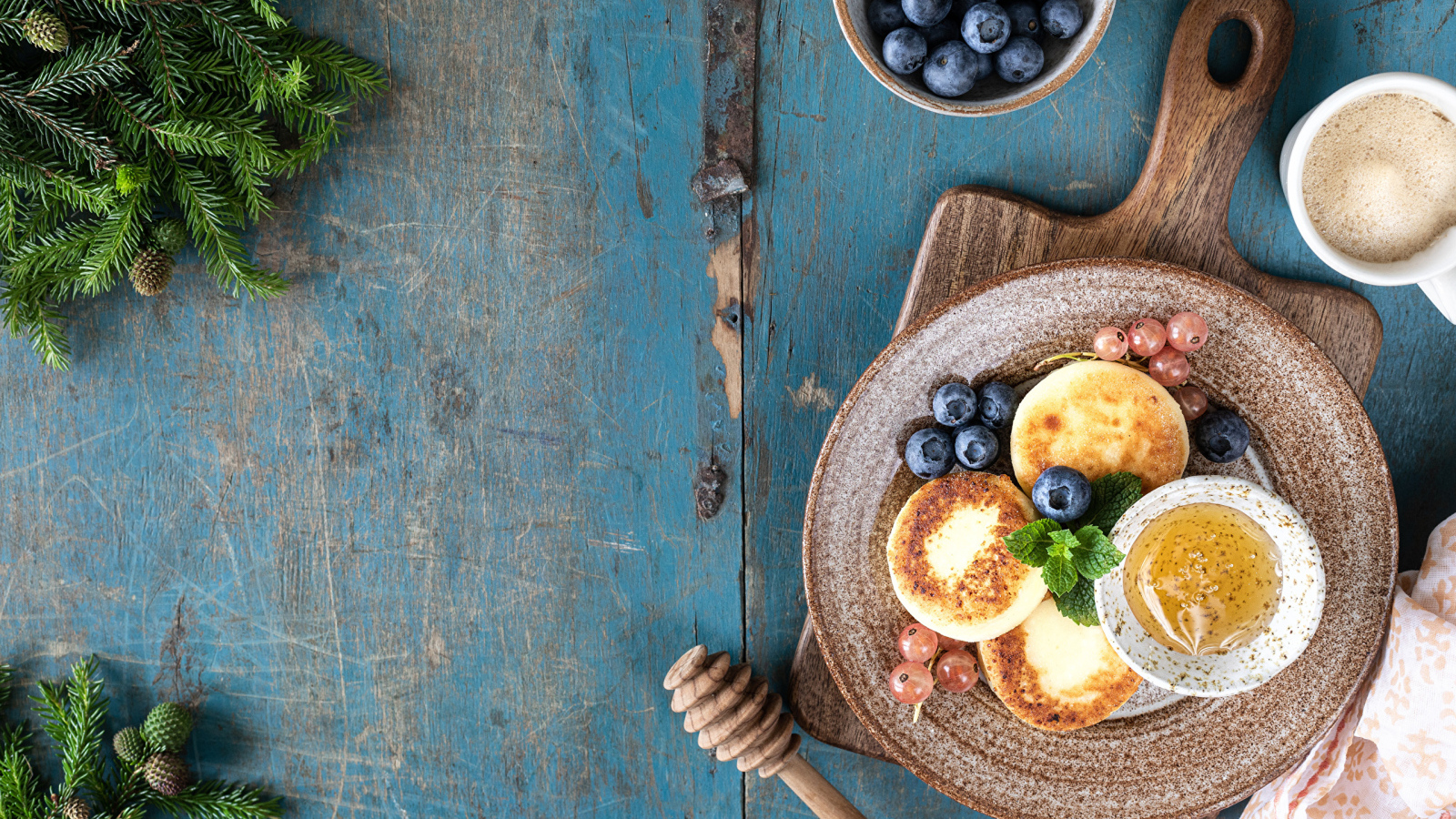 Сырники с ягодами черники на тарелке с медом