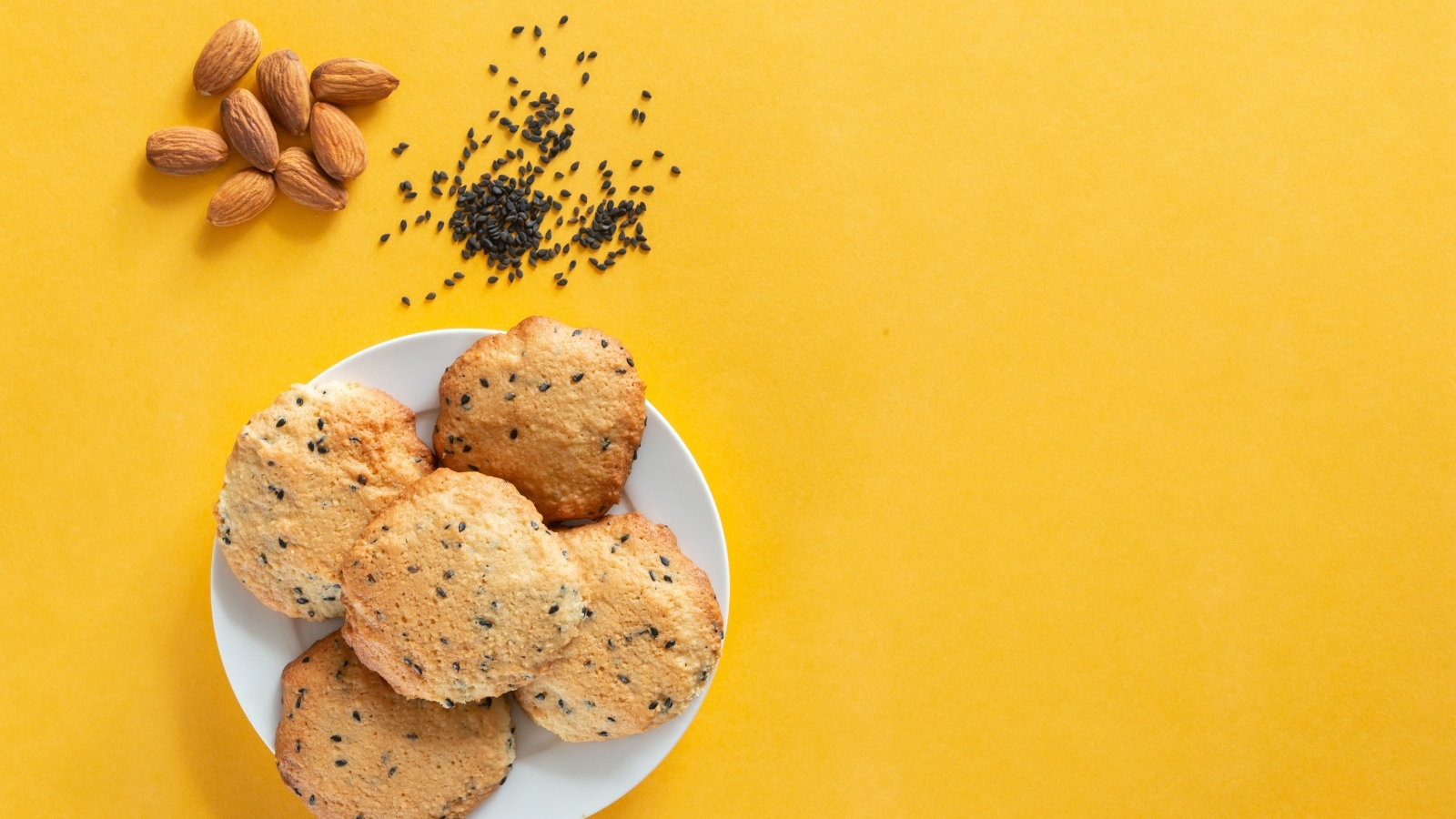 Печенье на желтом фоне с кунжутом и миндальным орехом