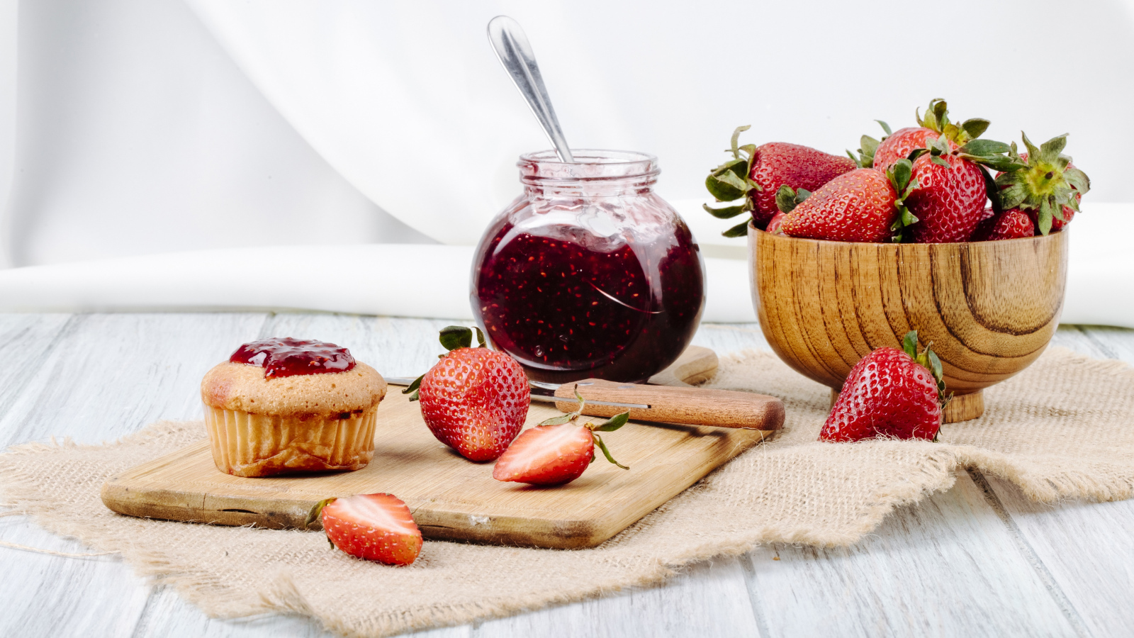 Кекс со свежей клубникой и джемом на столе