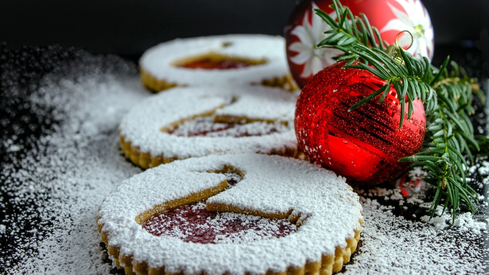 Вкусное сладкое печенье в сахарной пудре на столе с елочными игрушками