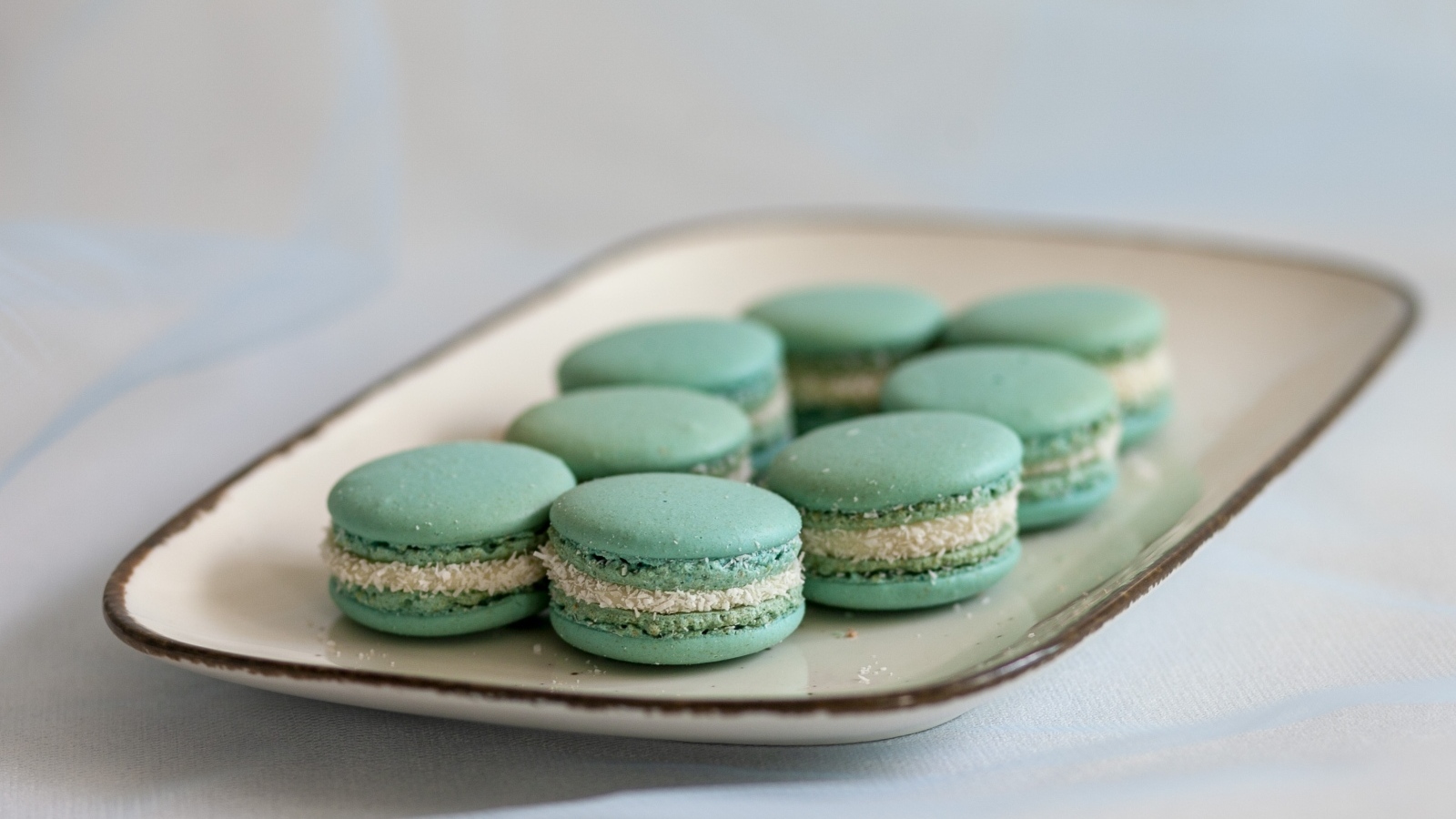 Зеленый десерт макаронс на большой тарелке на столе