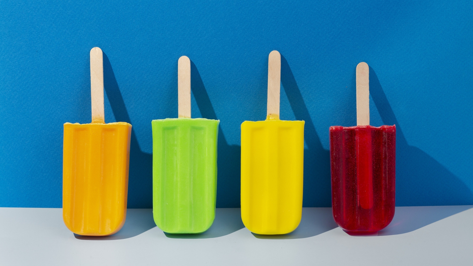 Разноцветное фруктовое мороженое на фоне голубой стены