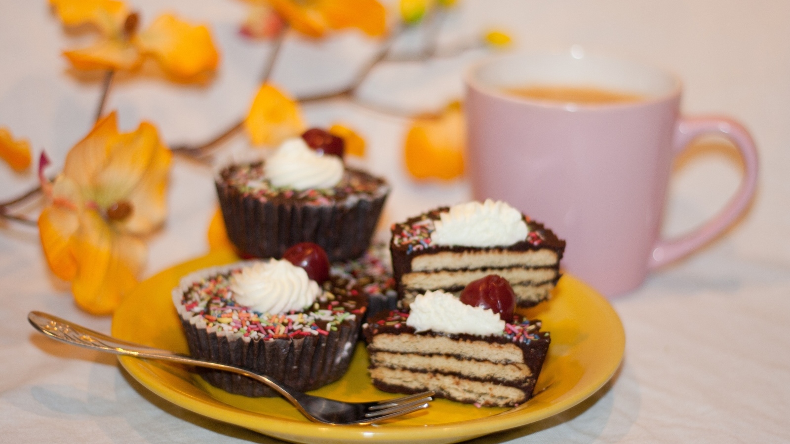 Сладкие вкусные пирожные на столе с чашкой чая и цветами