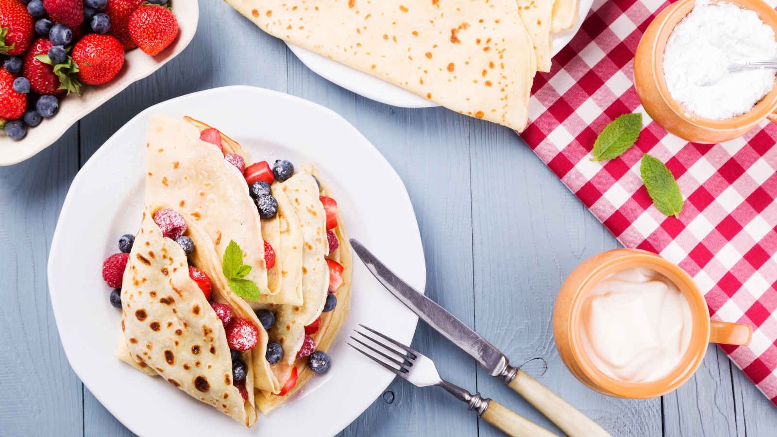 Сладкие тонкие блинчики с ягодами на тарелке