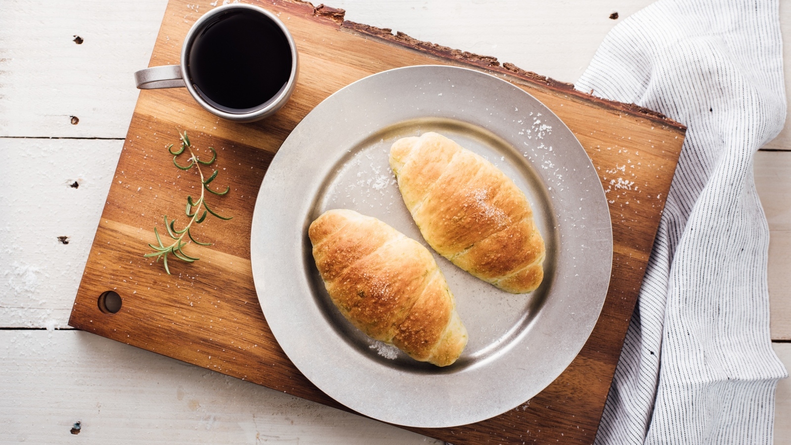 Два круассана на тарелке с чашкой кофе