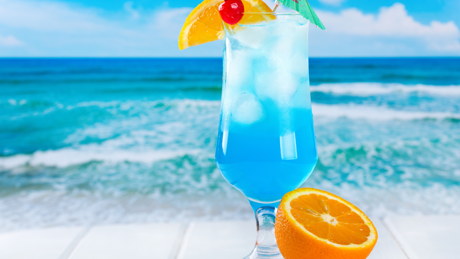 Голубой коктейль со льдом и половинкой апельсина