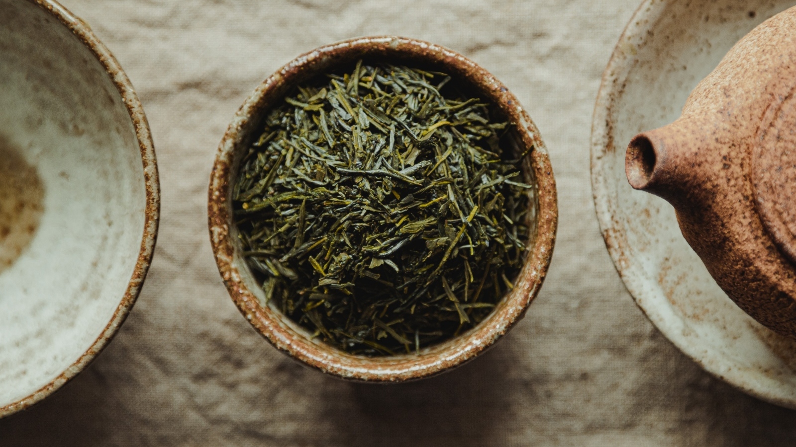 Зеленый чай в пиале на столе с чайником