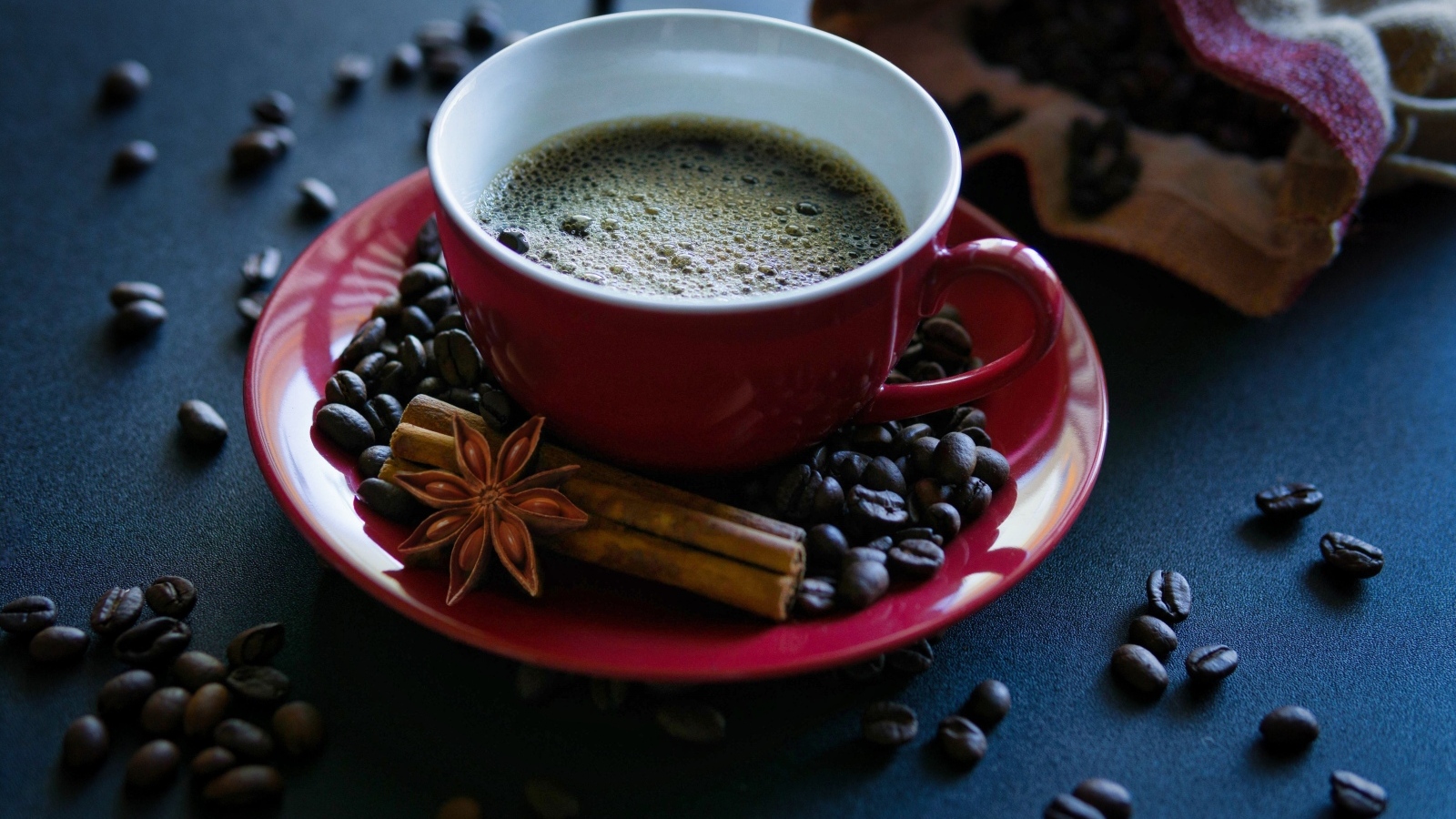 Красная чашка кофе на столе со специями и зернами