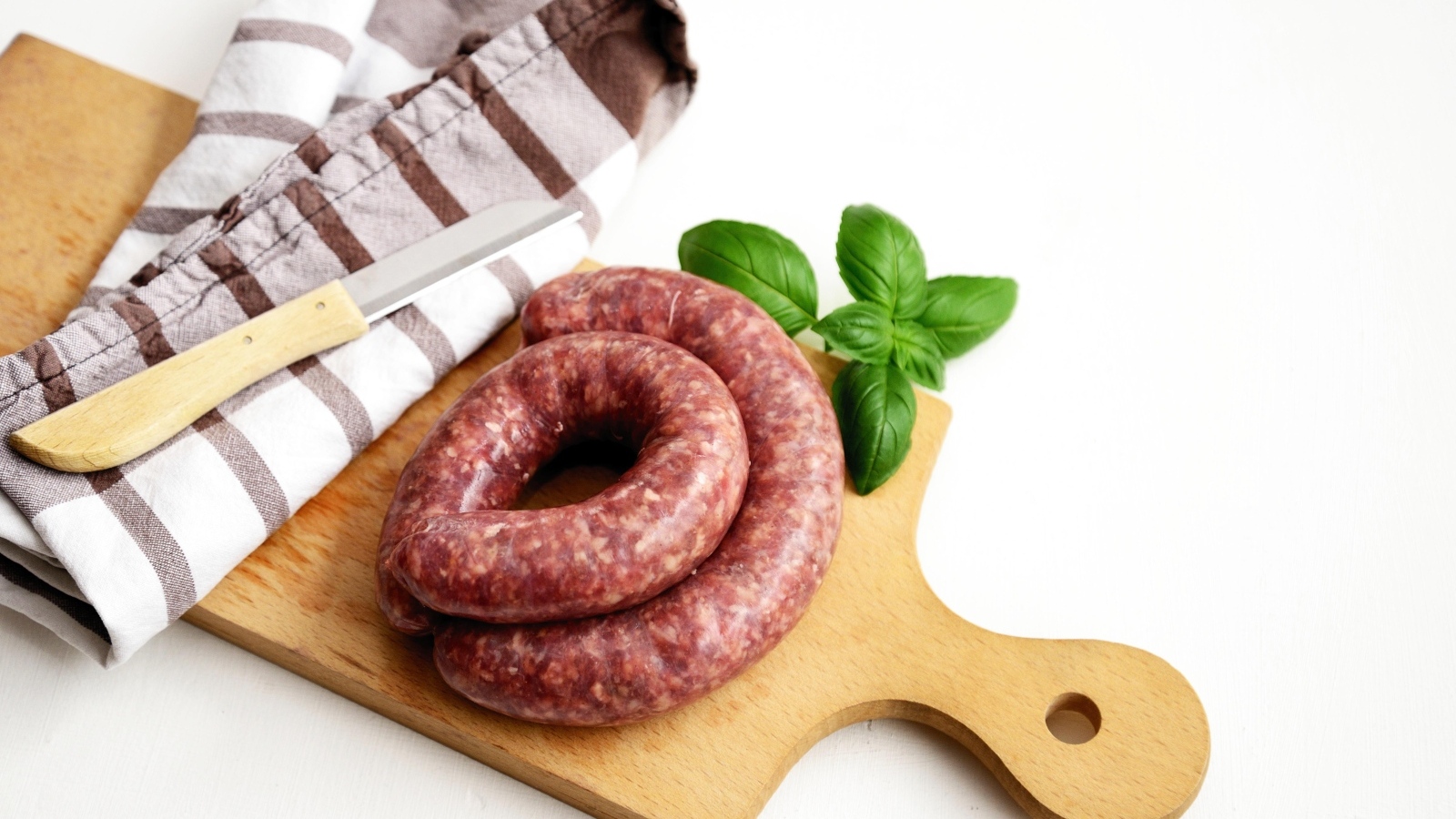 Сырая колбаса на доске с ножом