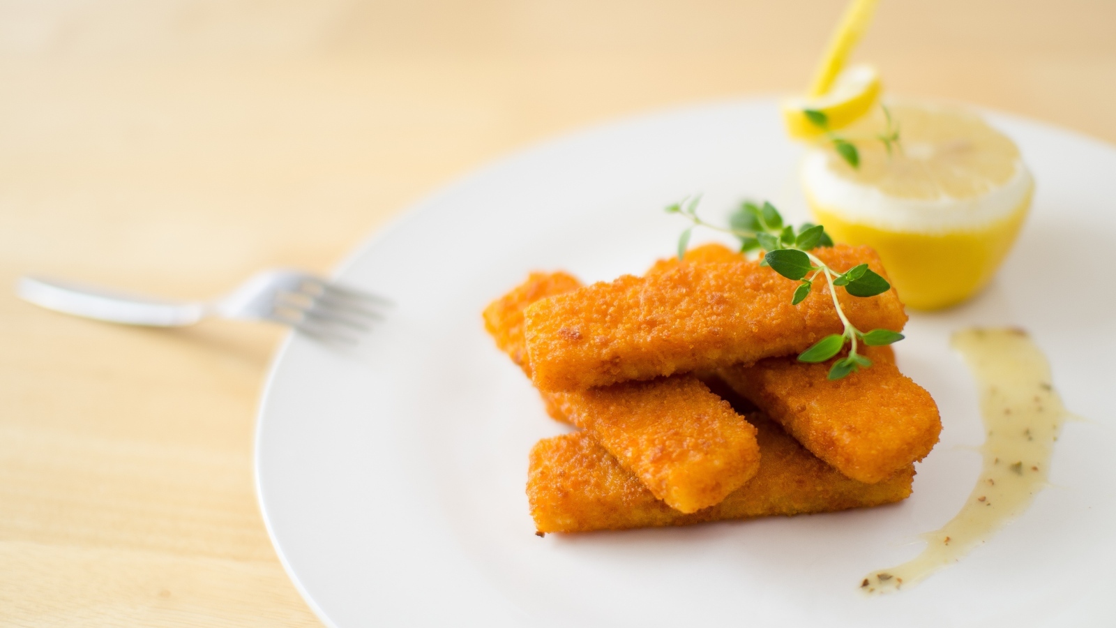 Жареные рыбные палочки на тарелке с лимоном