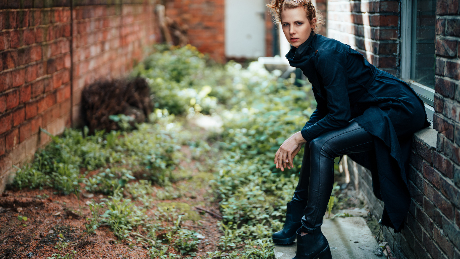 Девушка в черном наряде сидит на окне