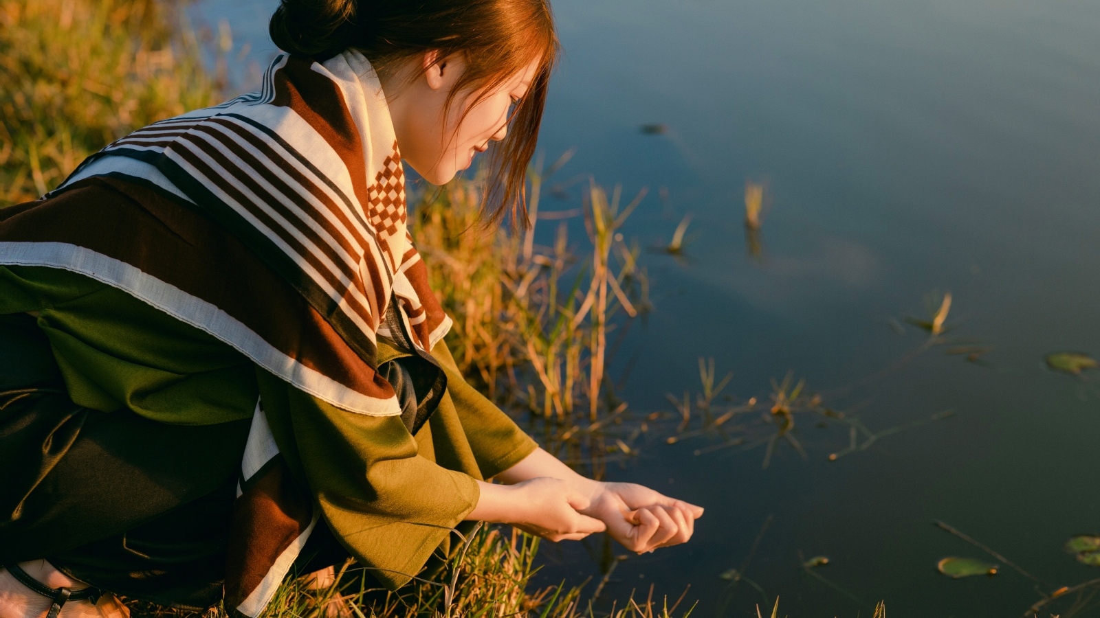 Девушка азиатка сидит у пруда