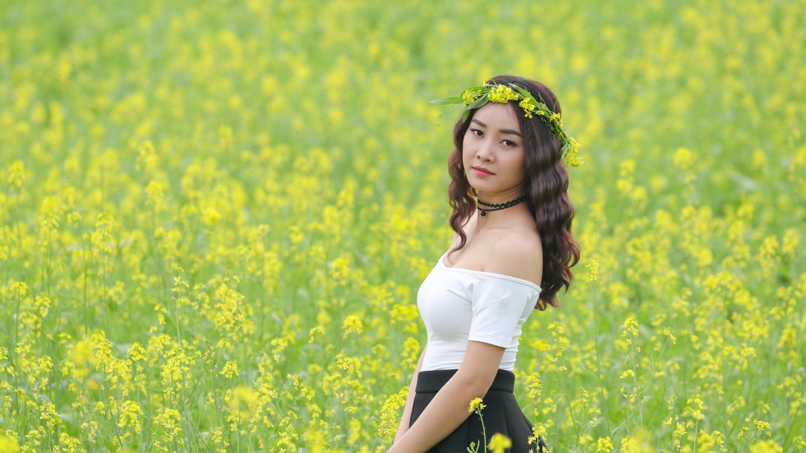 Девушка азиатка стоит на рапсовом поле