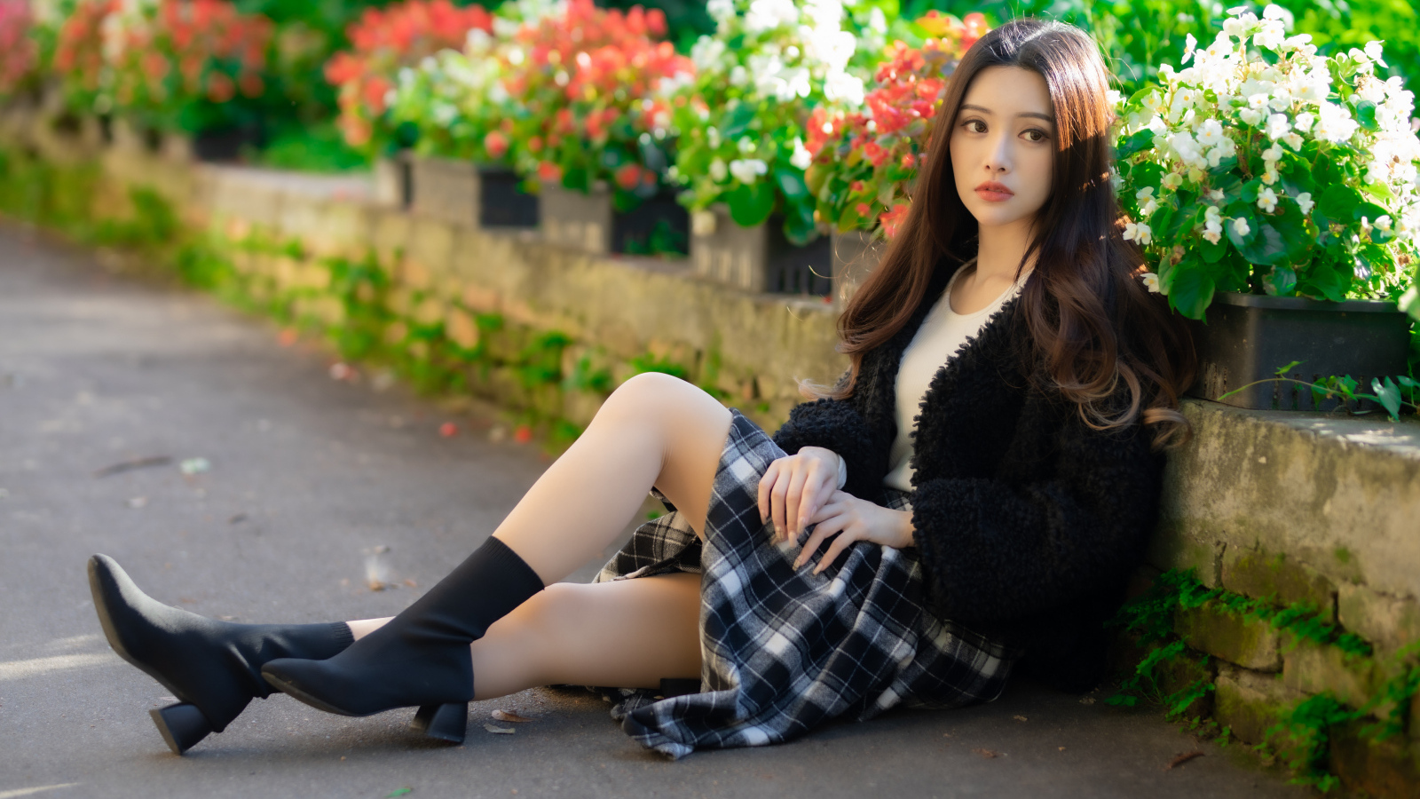 Азиатка сидит на асфальте у цветов