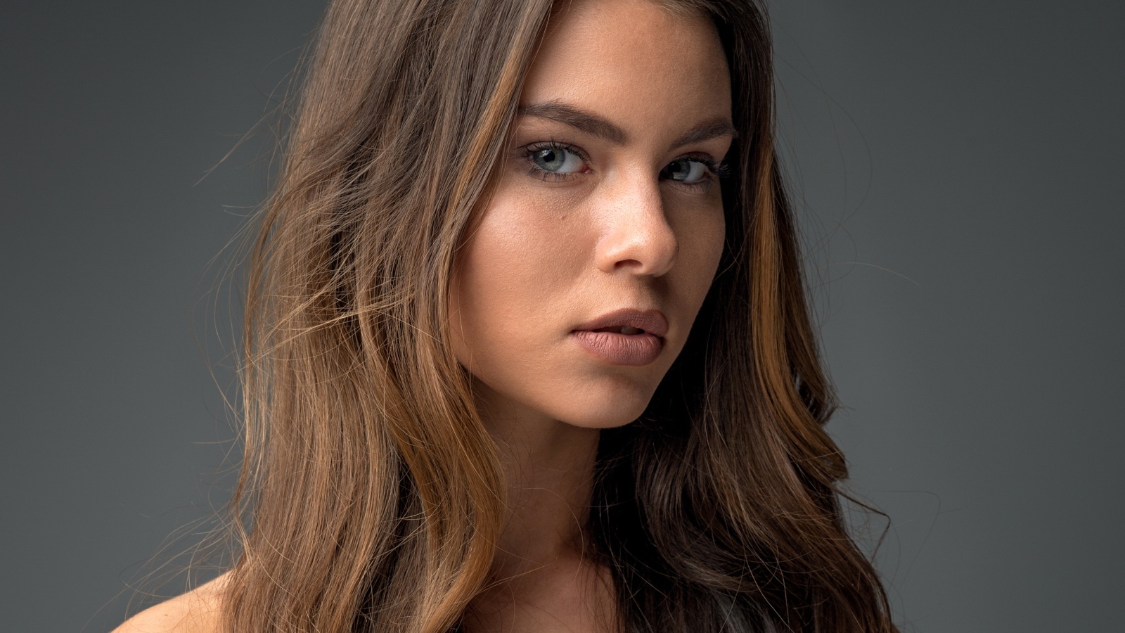 Красивая девушка шатенка на сером фоне 