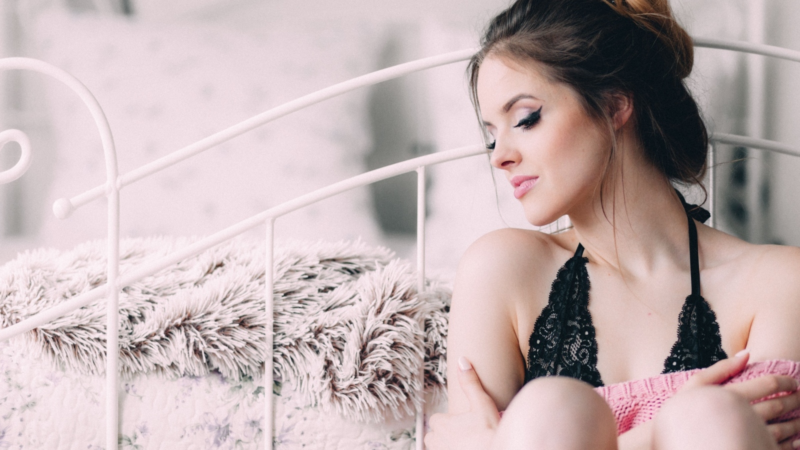 Красивая девушка сидит на полу у кровати 