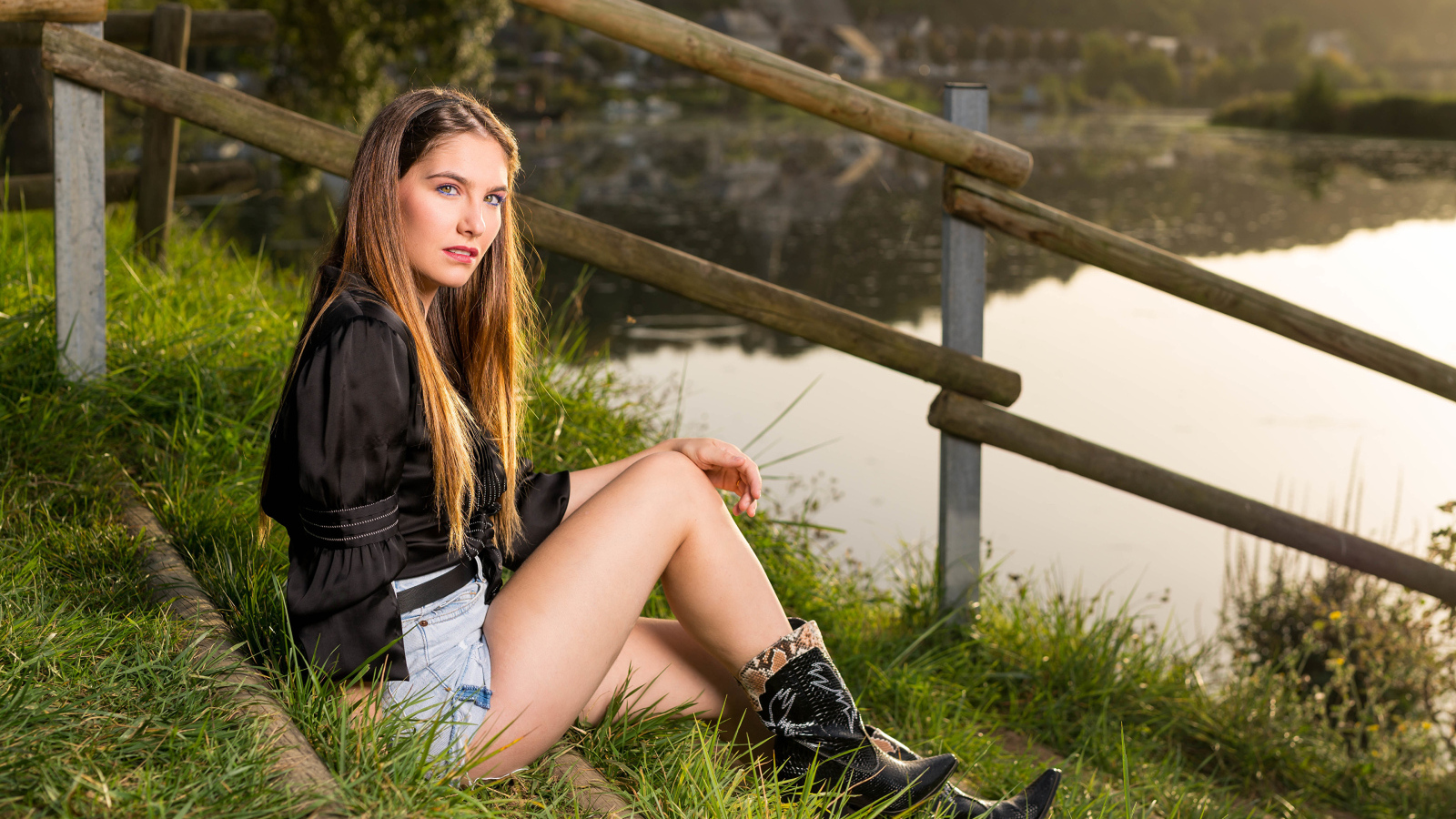 Красивая девушка сидит на берегу реки