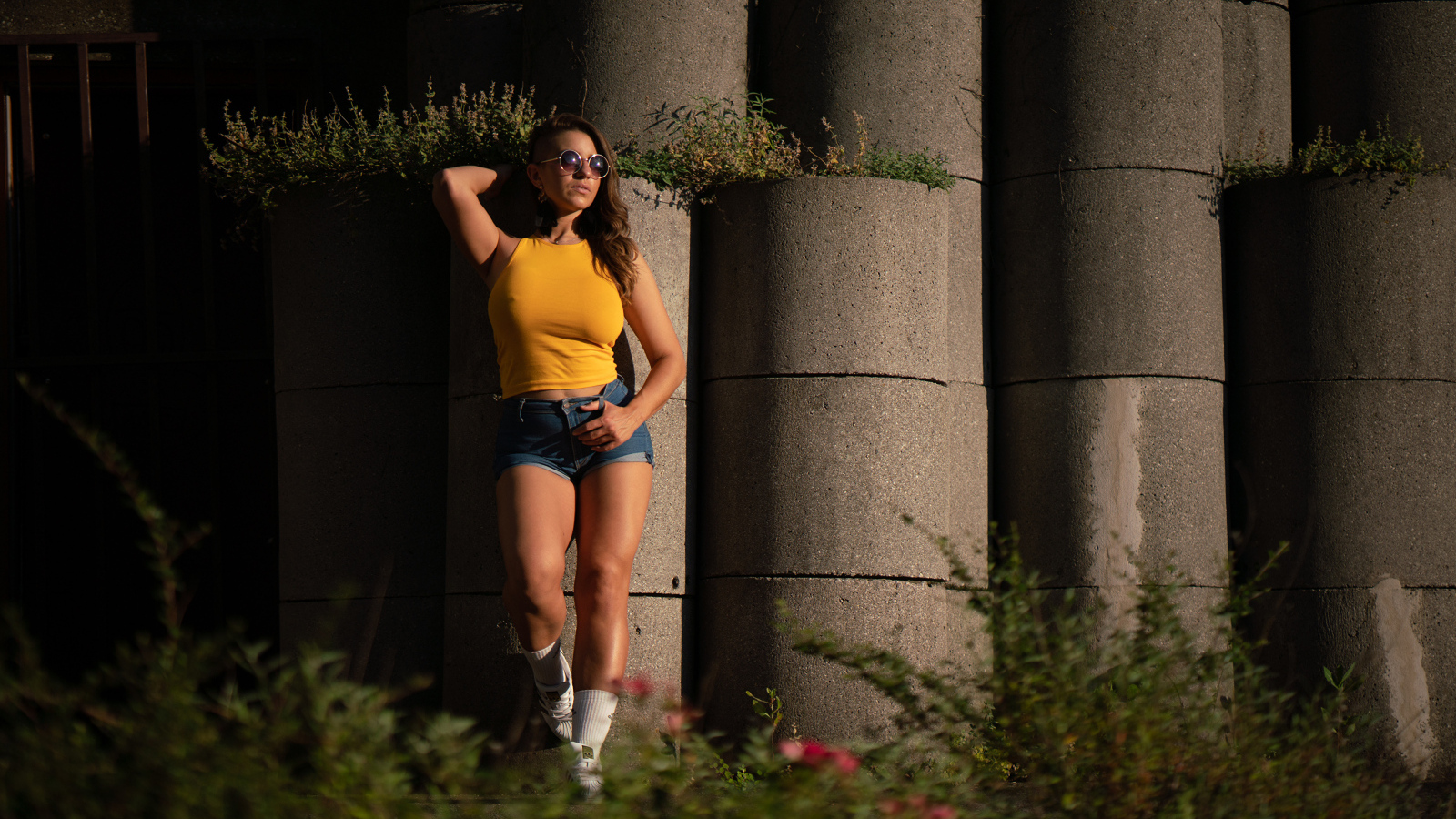 Красивая девушка в очках стоит у стены