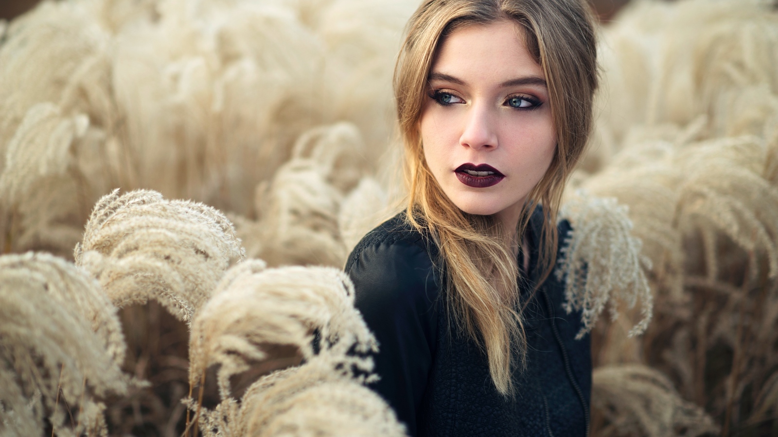 Красивая девушка с макияжем на лице позирует на природе