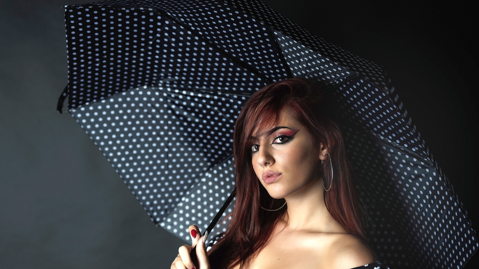 Яркая девушка под зонтом на сером фоне