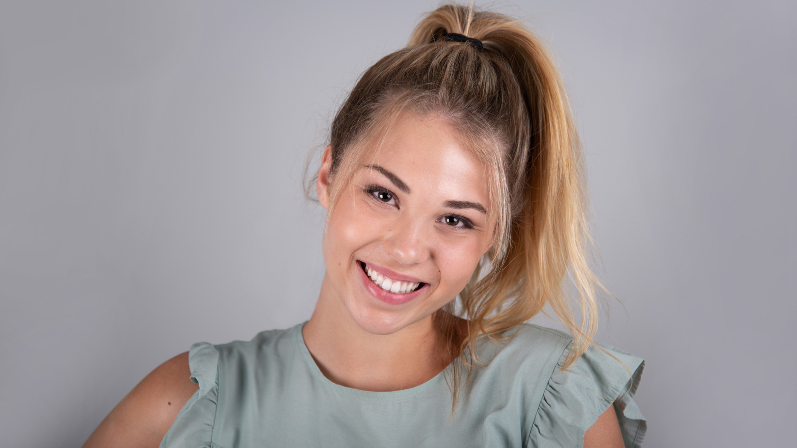 Милая блондинка на сером фоне