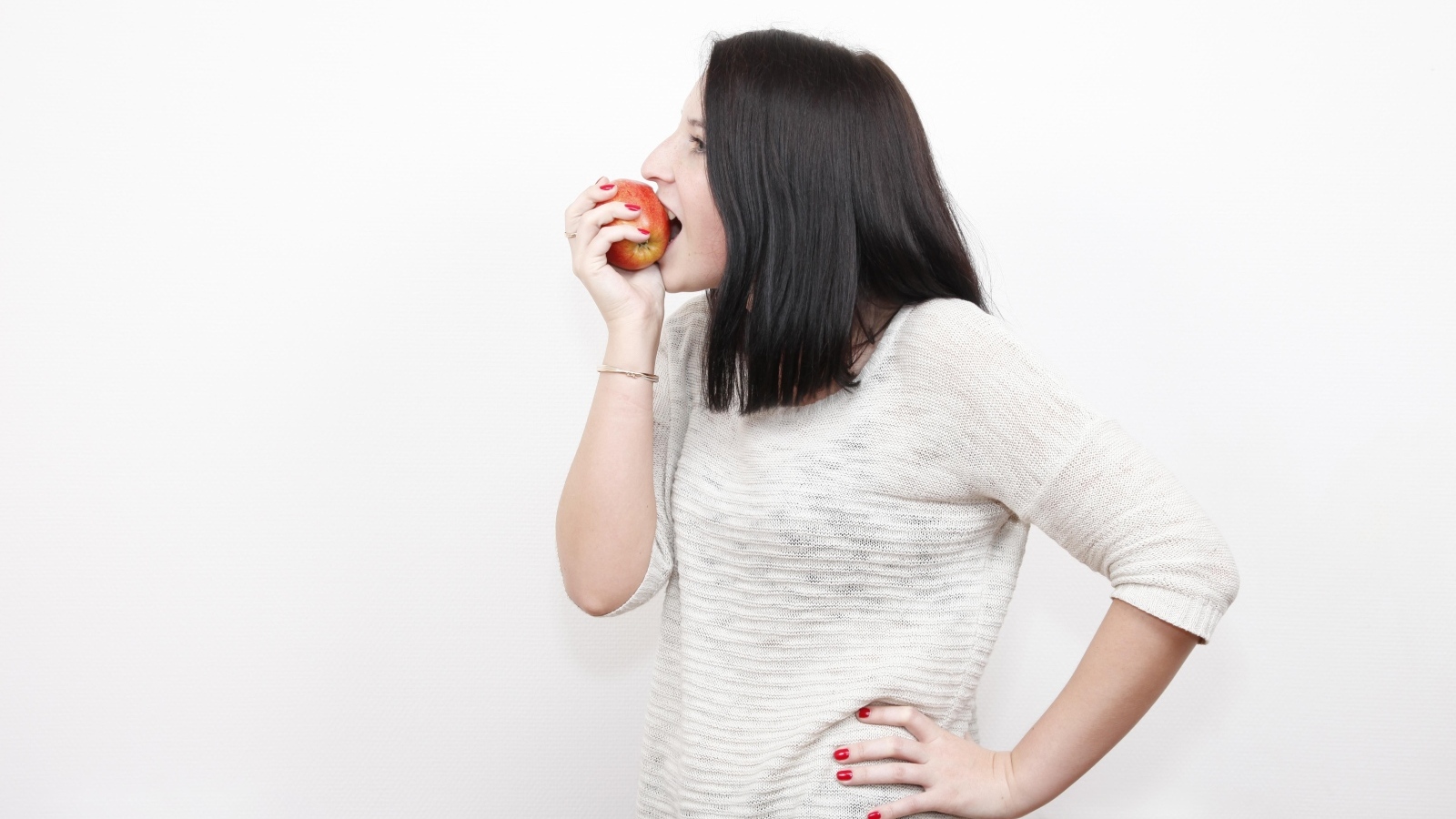 Девушка кусает красное яблоко 