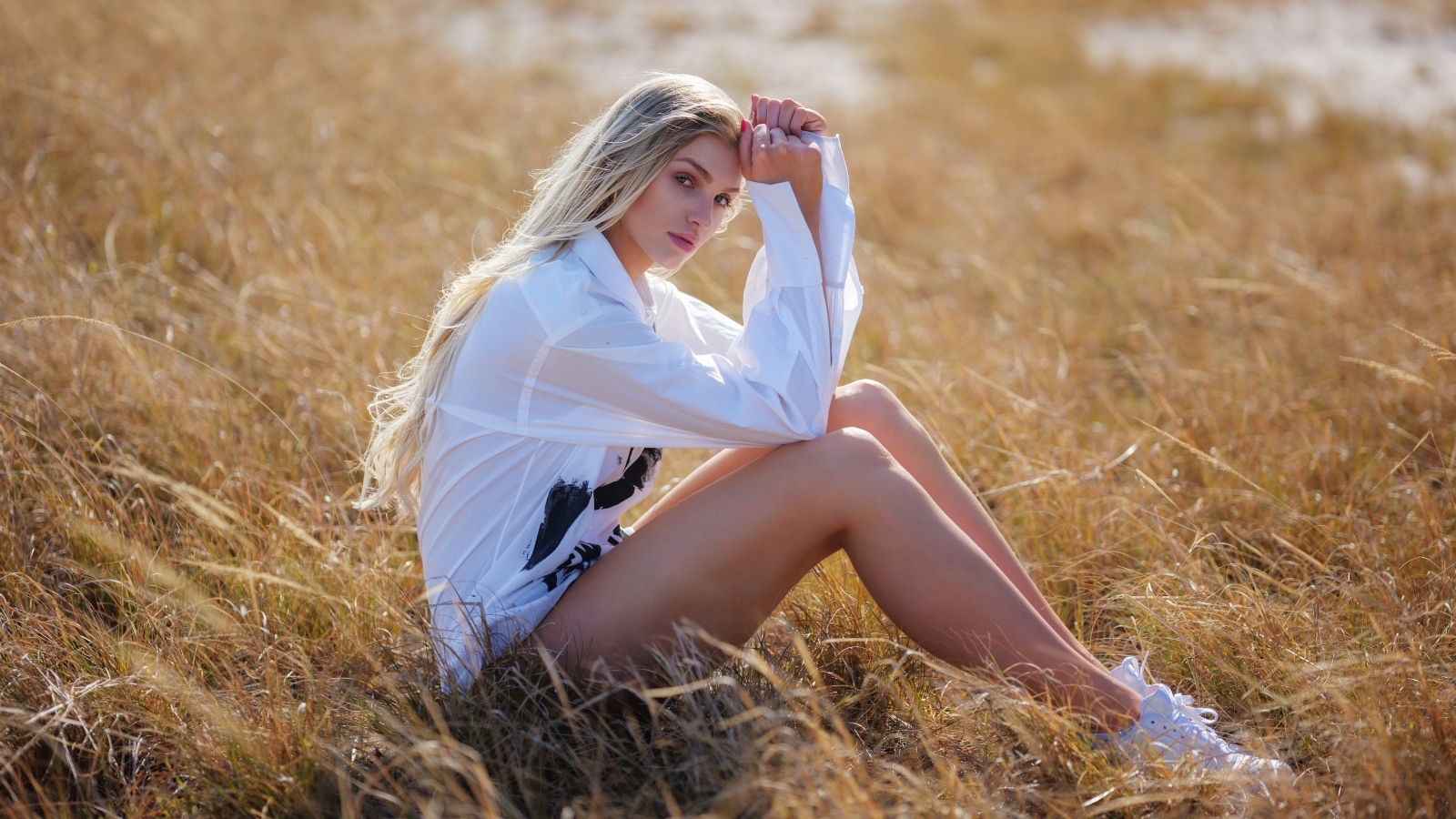 Девушка в белой блузке сидит на траве