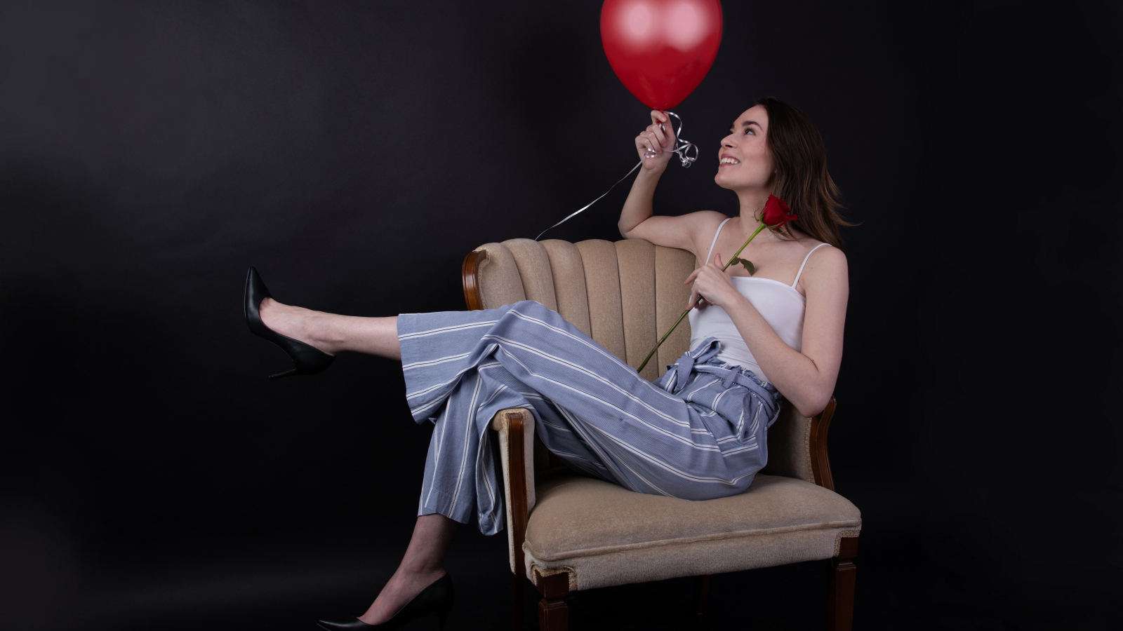 Девушка с шариком и розой сидит в кресле