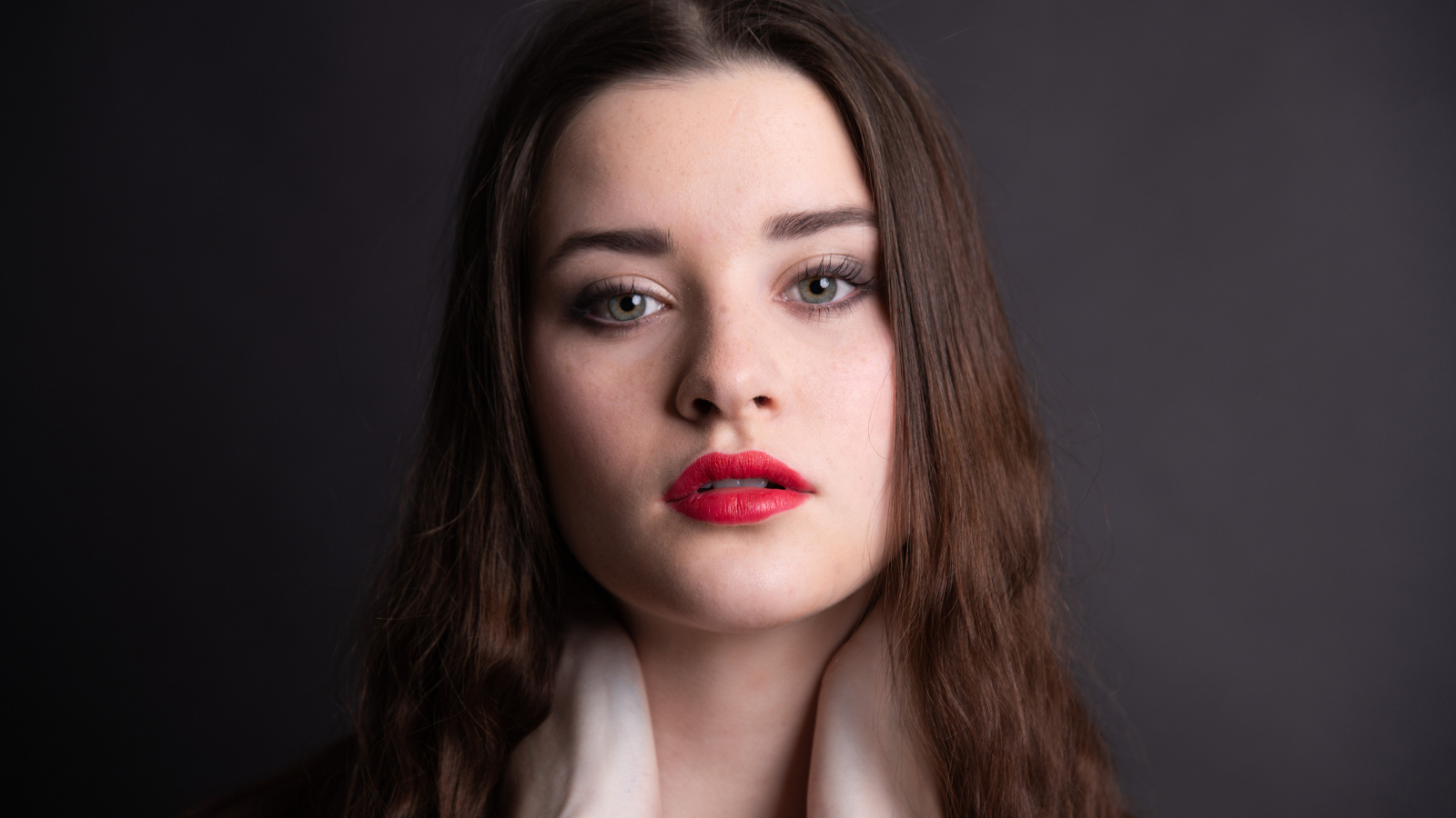 Девушка с красными губами на сером фоне