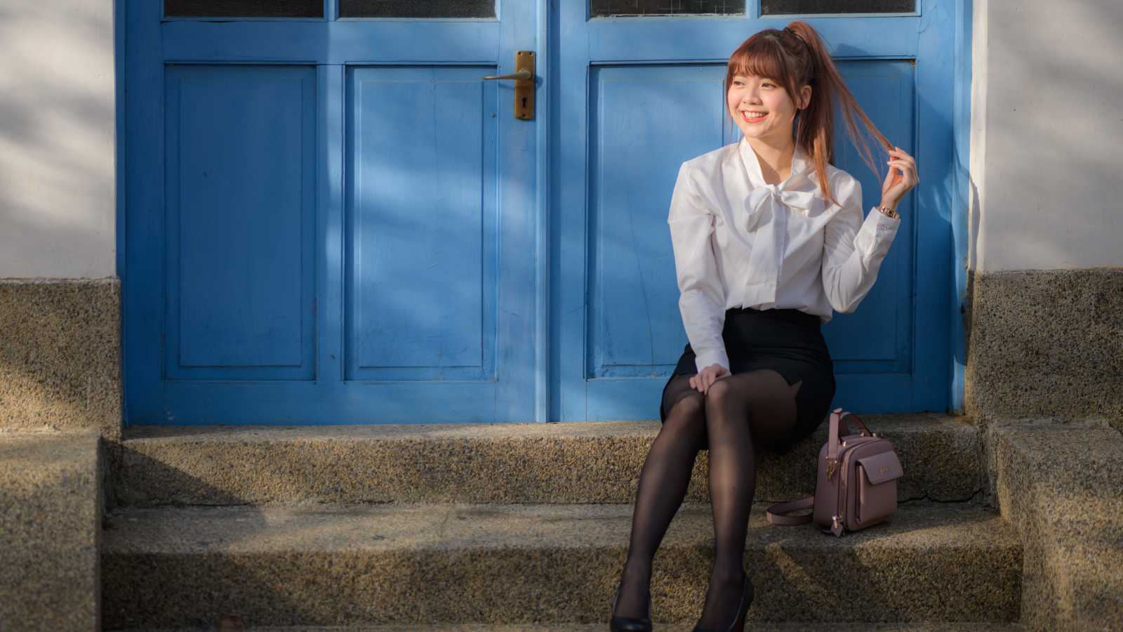 Улыбающаяся азиатка сидит на ступеньках
