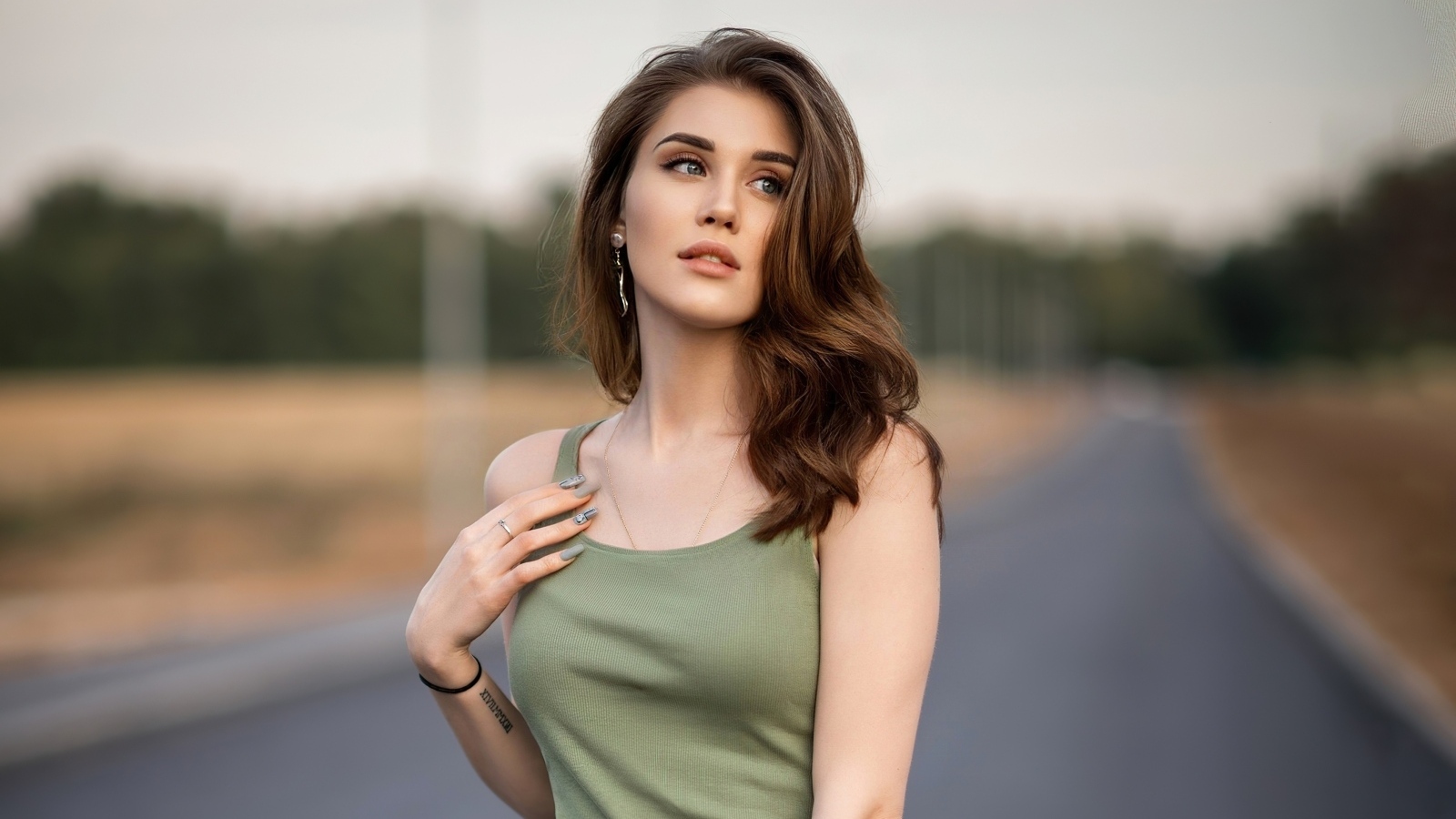 Нежная длинноволосая девушка стоит на дороге