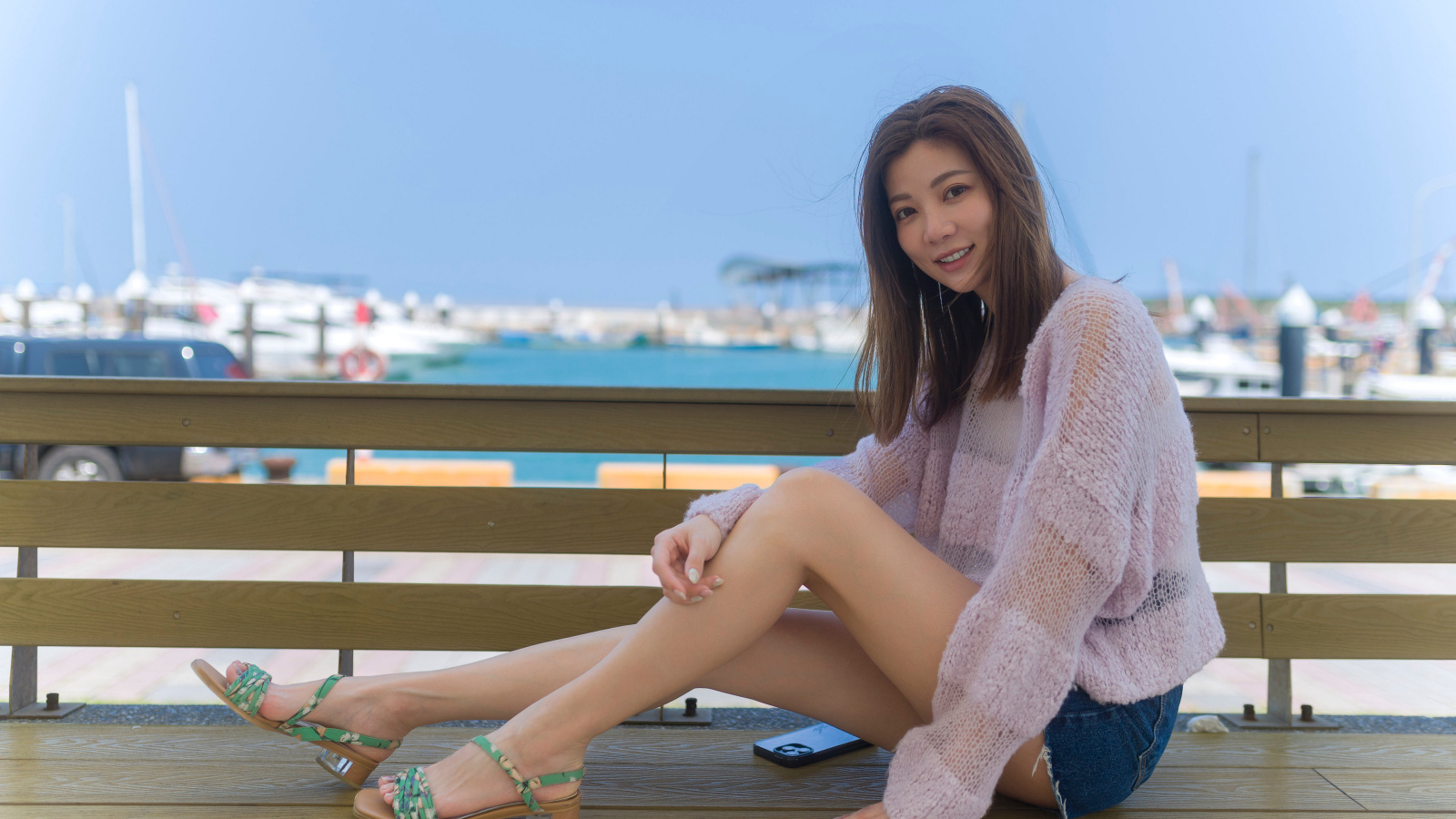 Молодая улыбающаяся азиатка сидит на лавке