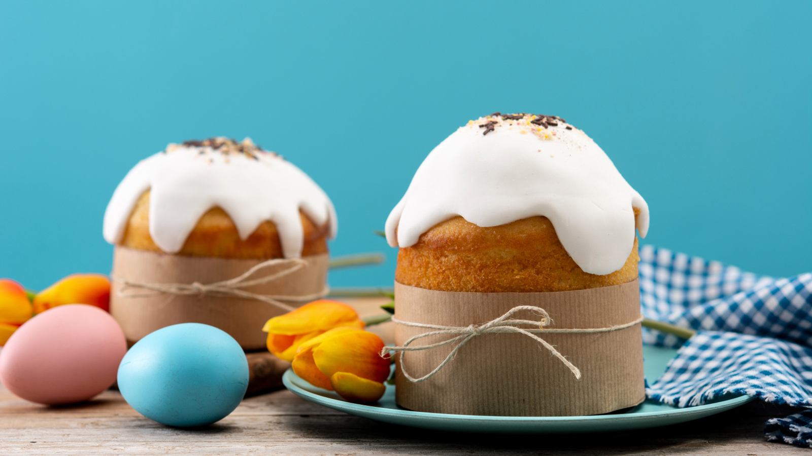 Пасхальные куличи с белой глазурью на столе с яйцами