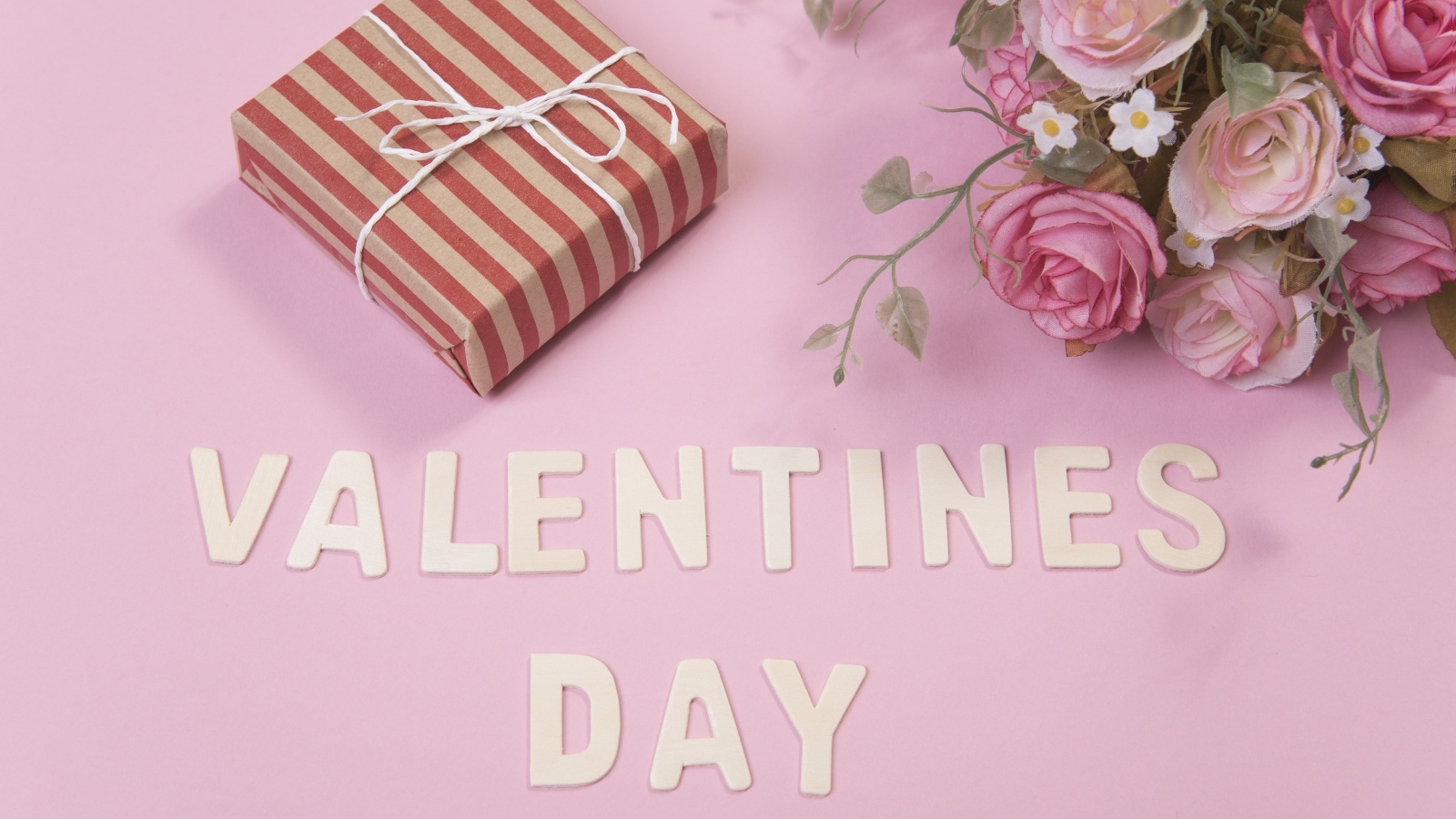 Цветы и подарок на розовом фоне на День Святого Валентина