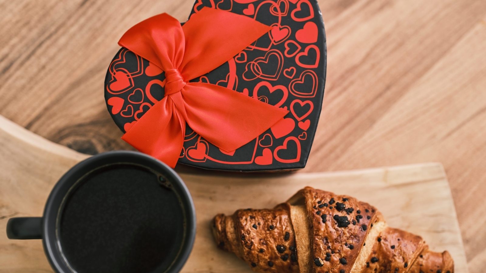 Коробка в форме сердца, кофе и круассан на столе