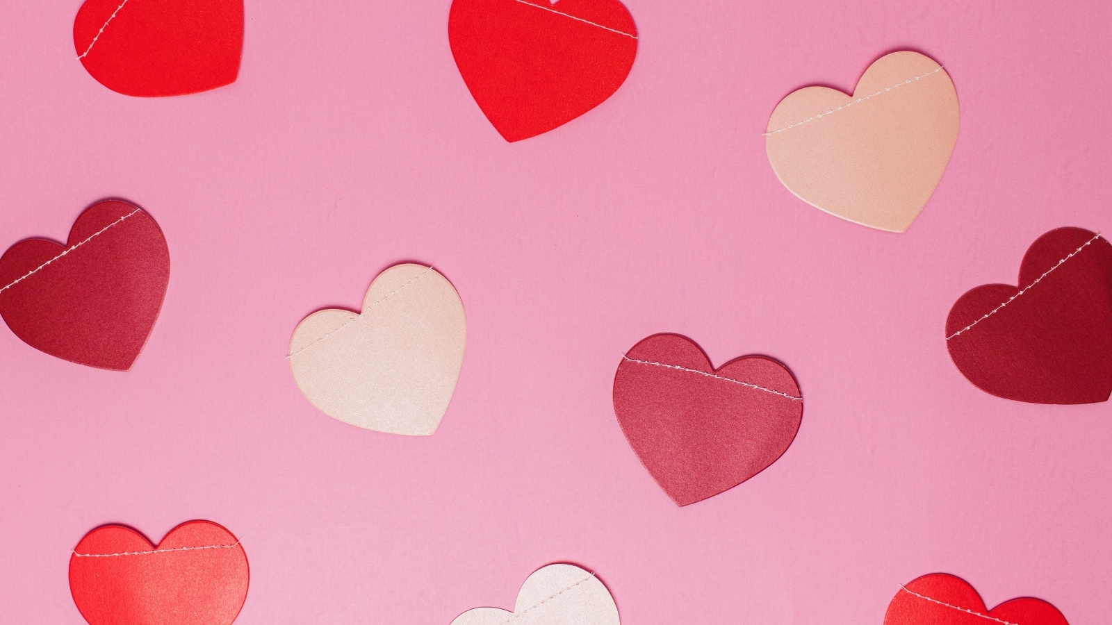 Бумажные разноцветные сердечки на розовом фоне