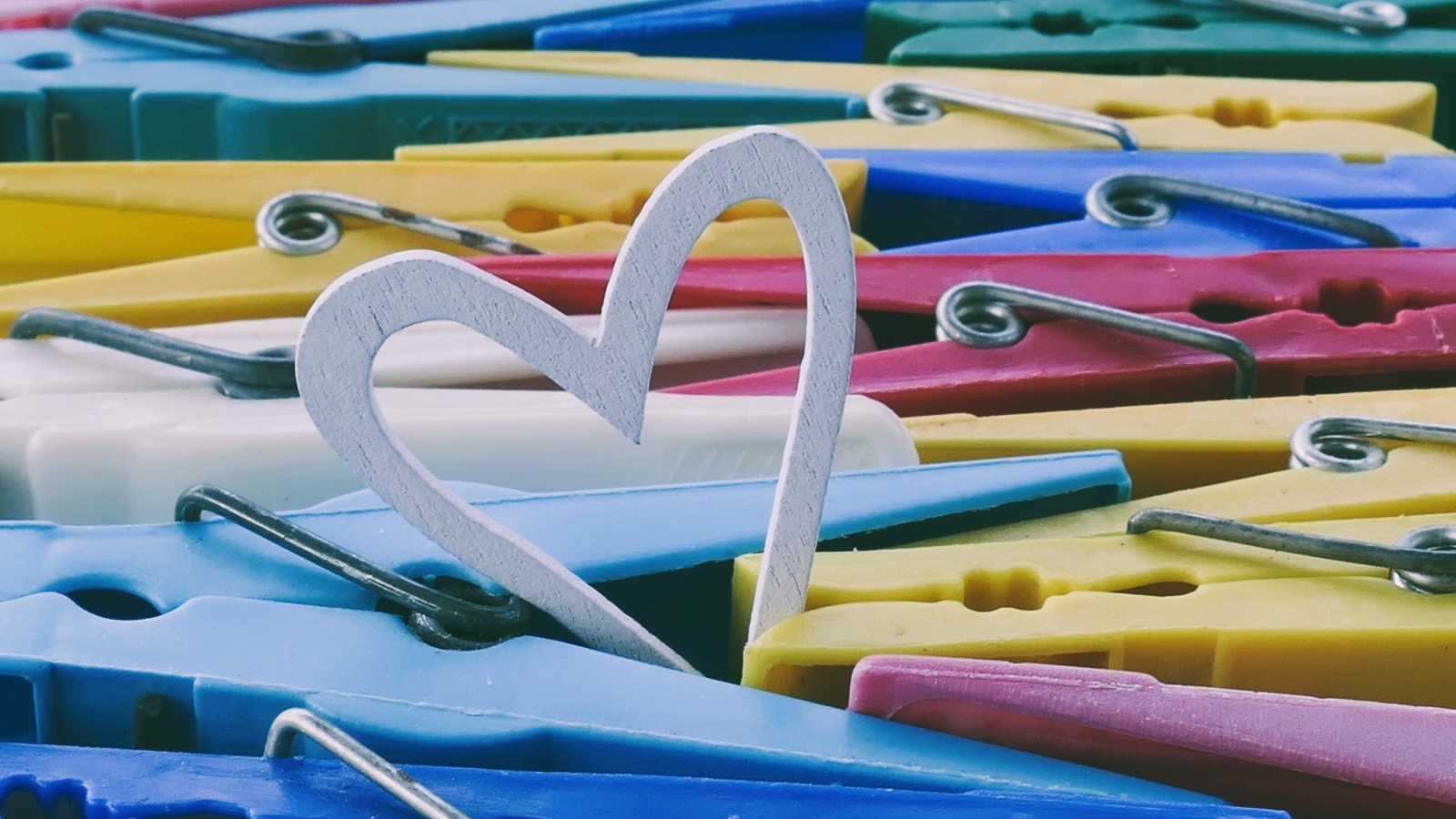 Белое деревянное сердце с разноцветными прищепками